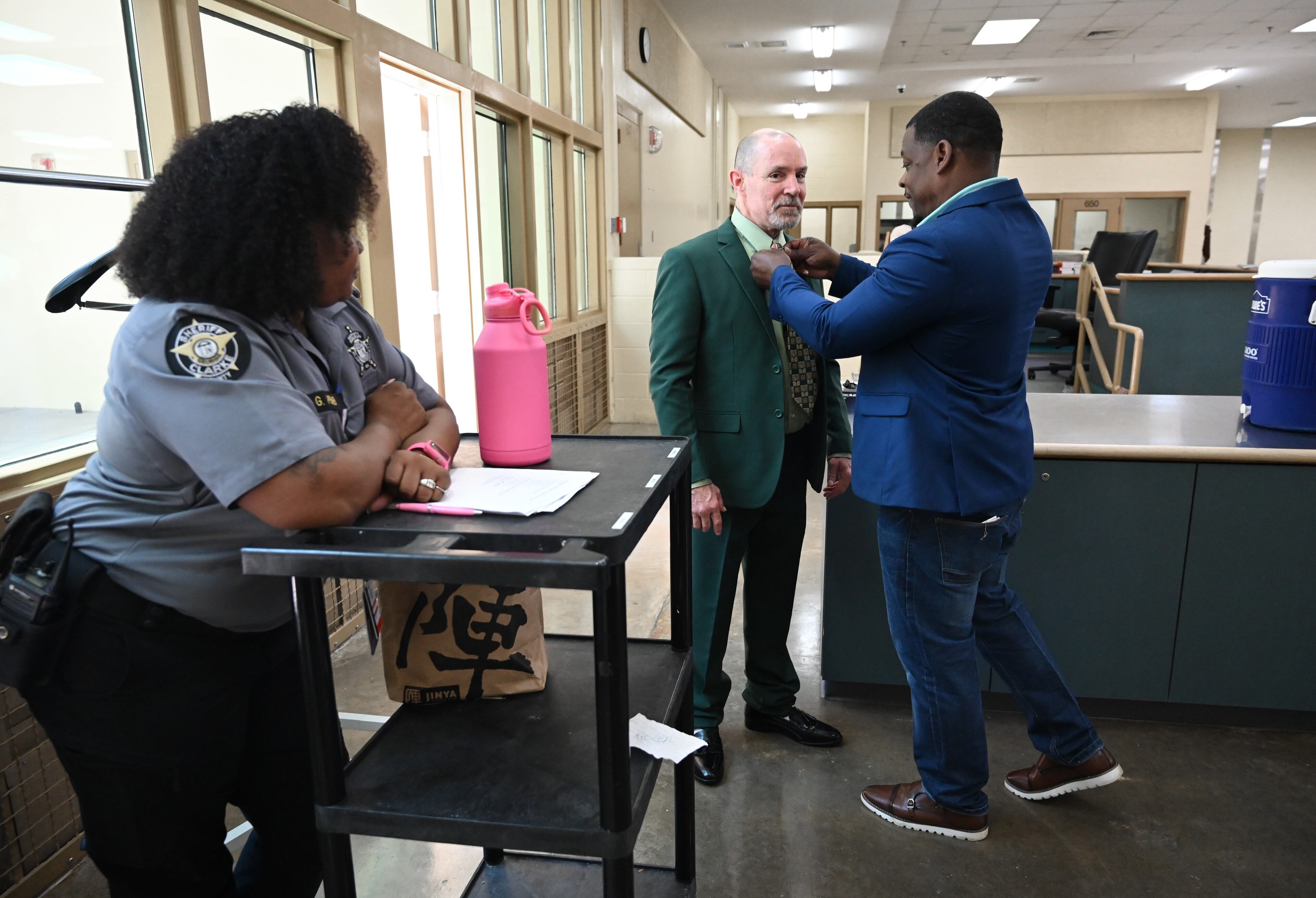 Shane Sims (right), founder of Principles over Passion, helps graduate Kirby Kesler with tying a necktie as Deputy Gloria Pender (left) looks on before a graduation ceremony for the Re-Entry Success Program at the Athens-Clarke County Jail on Wednesday, June 18, 2025, in Athens. (Hyosub Shin/AJC)