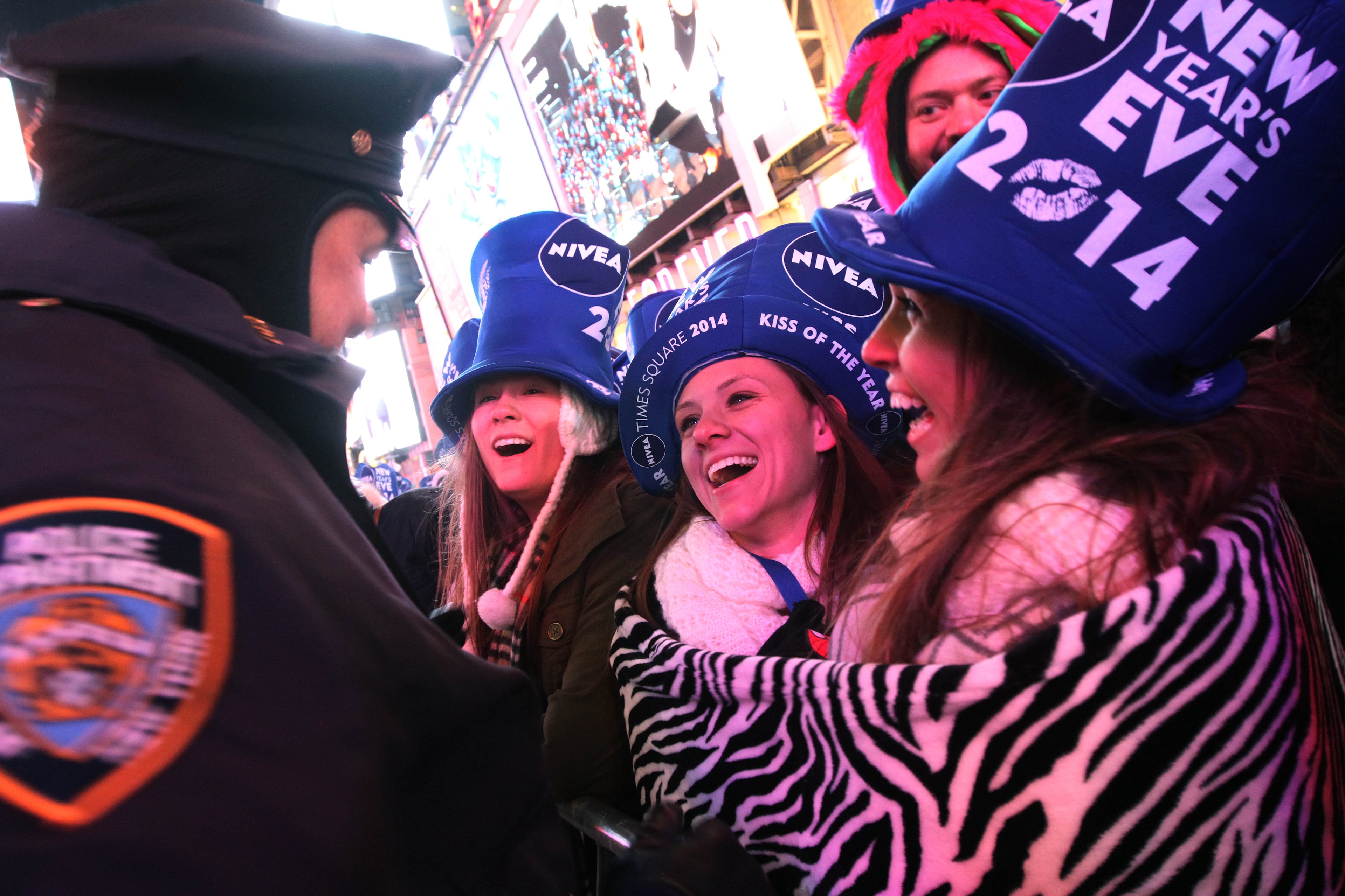 Wrapped in a blanket to stay warm, Jessica Munoz. right, and Erika Ranslow, second from right, share a moment with a member of the NYPD, left, as they take part in the New Year's Eve festivities Tuesday Dec. 31, 2013 in New York's Times Square. Both Munoz and Ranslow are from Fort Lauderdale, Florida. (AP Photo/Tina Fineberg)