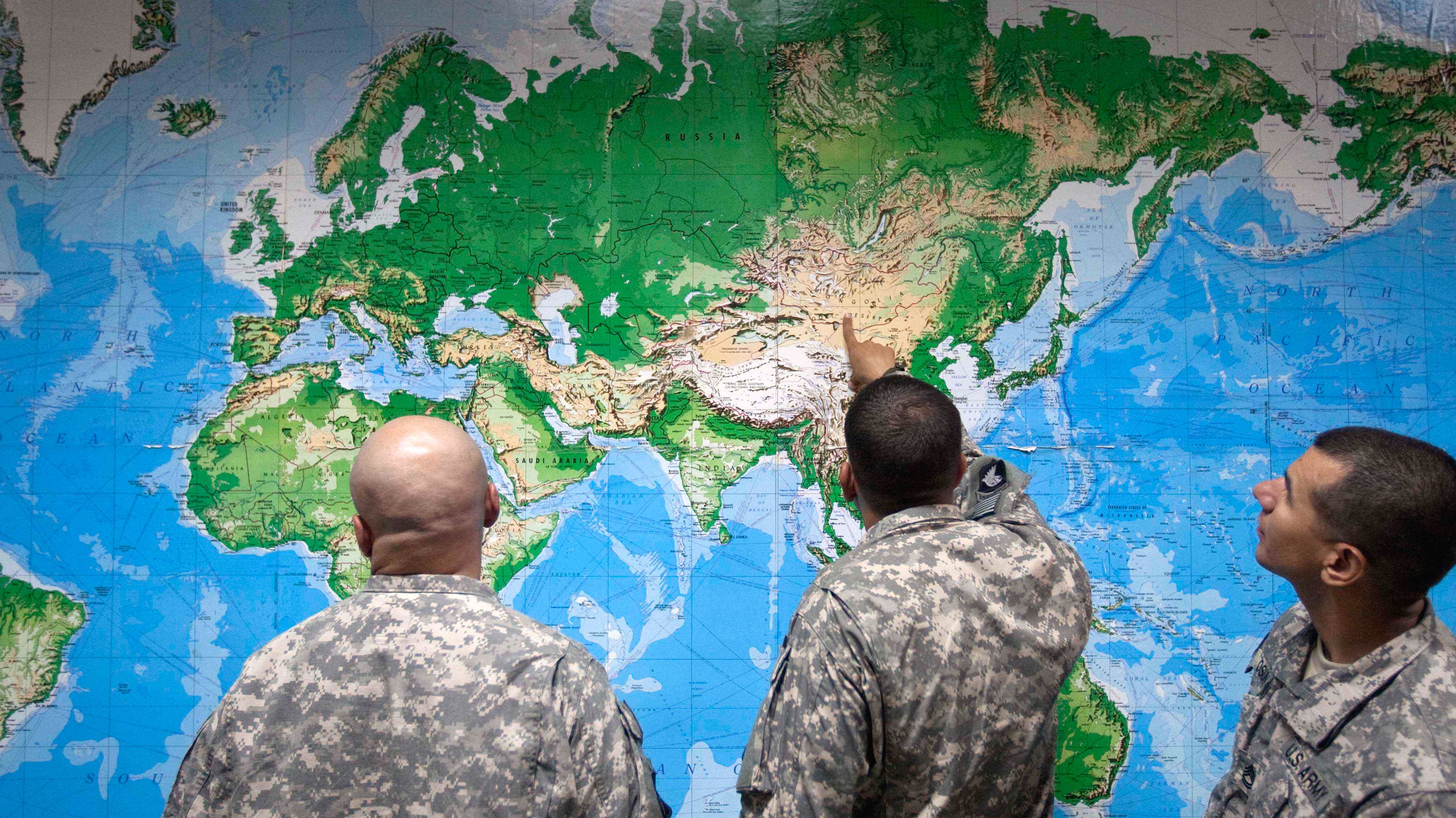 FILE - Soldiers look at a world map as they wait to board a flight in Manas, Kyrgyzstan, on the way home after completing a deployment in Afghanistan, Thursday, Aug. 11, 2011. (AP Photo/David Goldman, file)