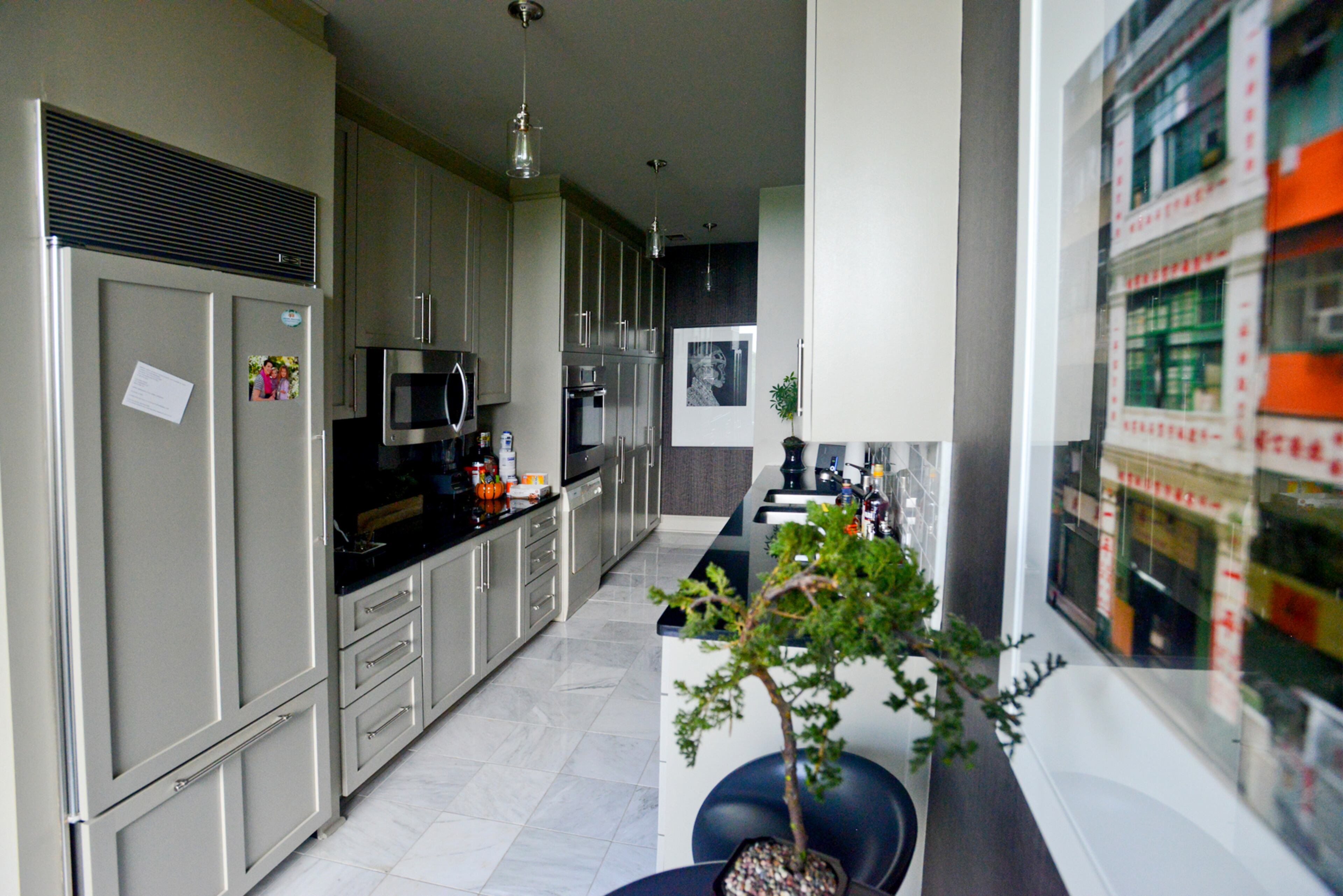 In the galley-style kitchen, homeowner Jason Moattar has refaced and painted the cabinets, added stainless steel appliances and changed the floor to marble.