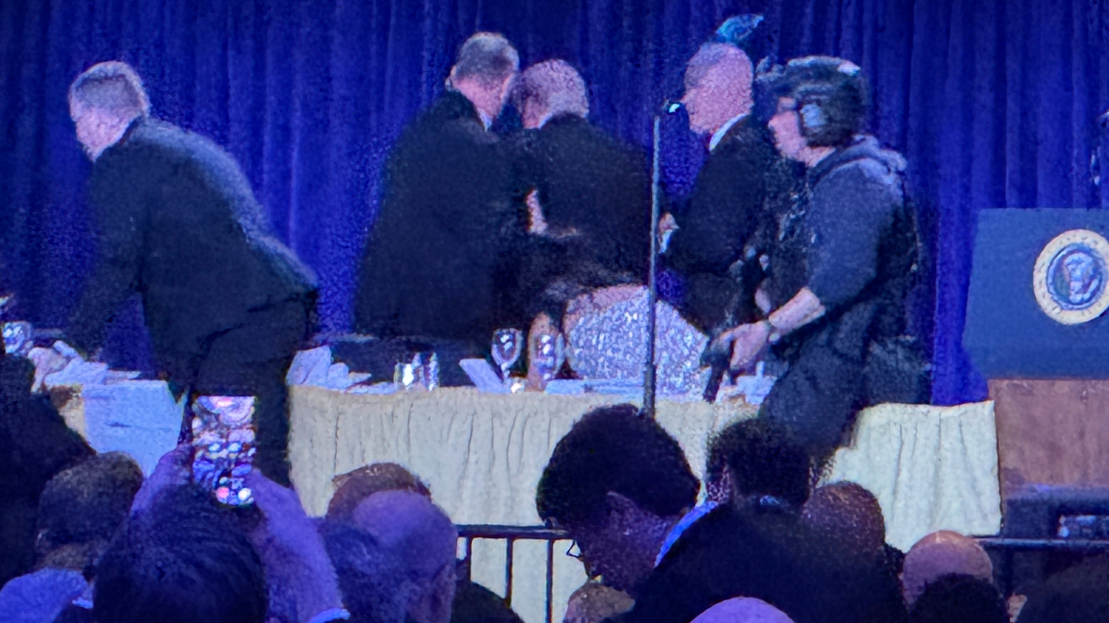 U.S. Secret Service agents surround President Donald Trump, third from left, as he is taken from the stage after a shooting incident outside the ballroom during the White House Correspondents Dinner, Saturday, April 25, 2026, in Washington. (AP Photo/Mark Schiefelbein)