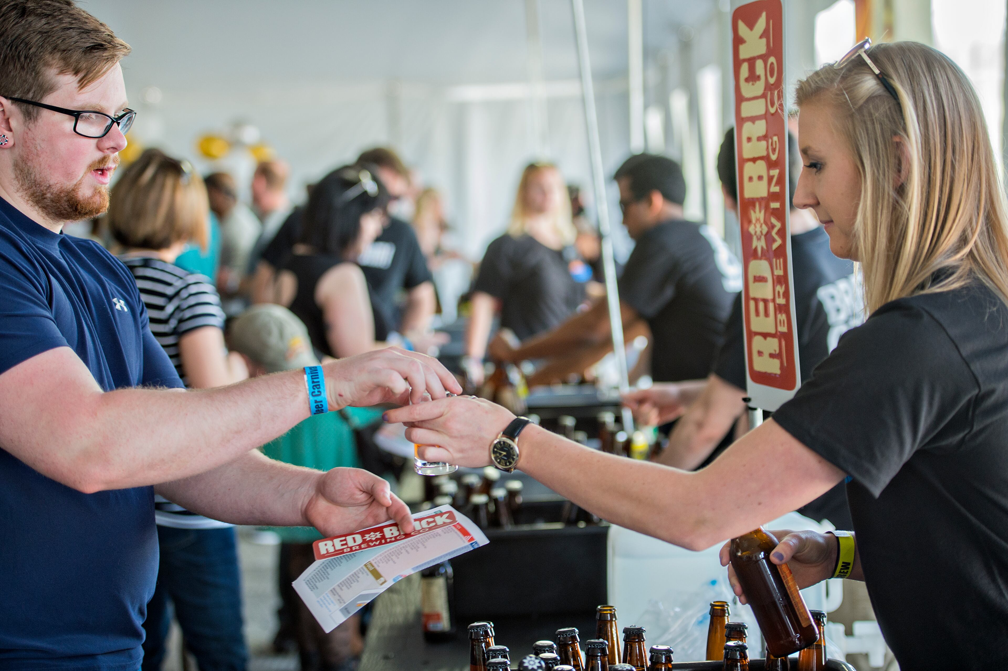 Caleb Tarleton (left) is handed a sample of beer by Lauren Lipcsei during the sixth annual Beer Carnival at Atlantic Station in downtown Atlanta on Saturday, March 21, 2015. Over 4,000 people attended the event which featured beer from breweries all over the country as well as carnival styled games, food, music and more. JONATHAN PHILLIPS / SPECIAL