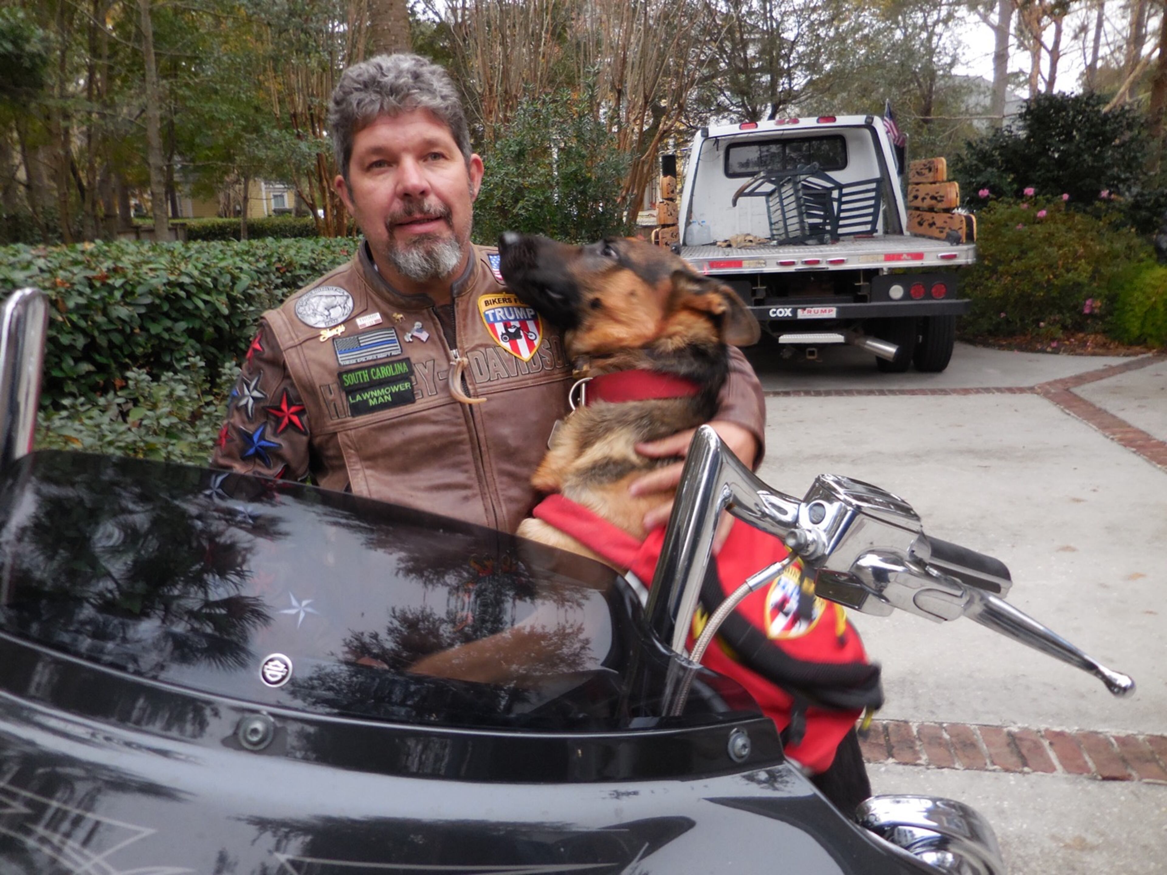 Chris Cox and his dog, Trigger. He often tows his motorcycle in the flatbed truck seen behind him. Photo: Jennifer Brett