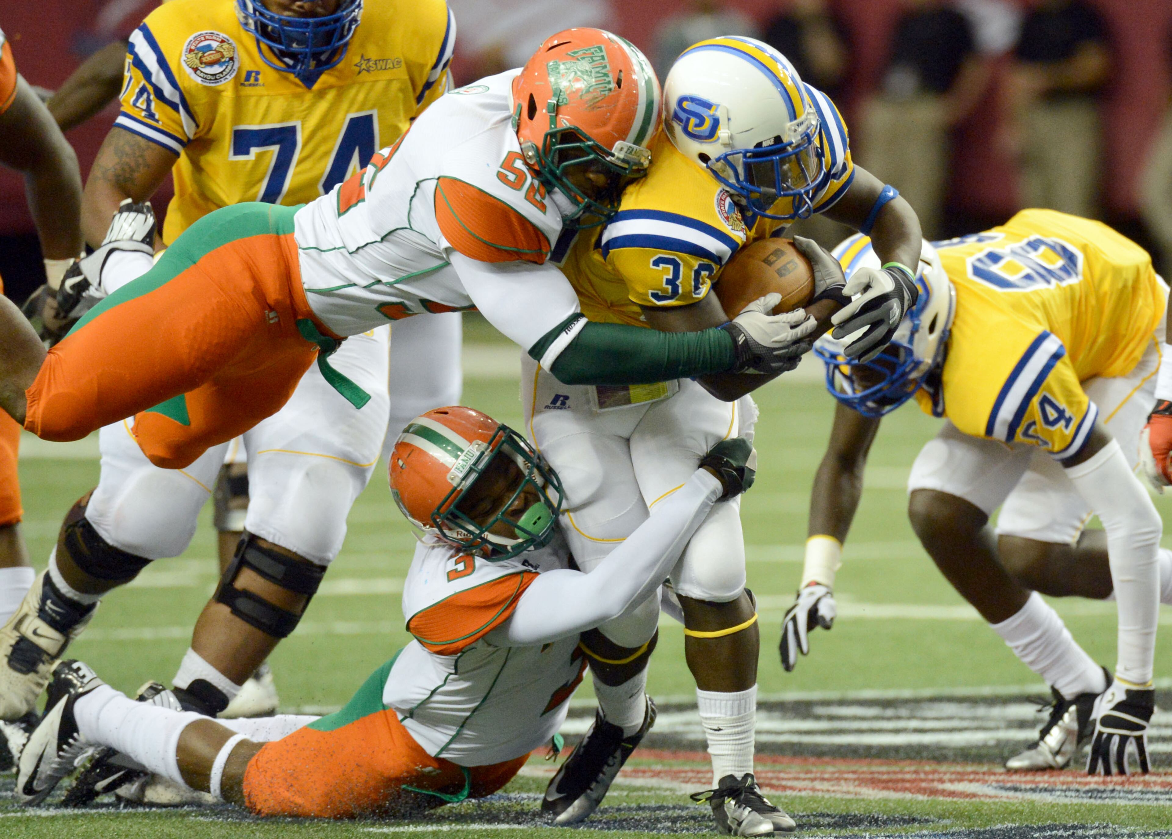 Southern running back Darrius Coleman (30) gets tackled by Florida A&M linebacker Brandon Hepburn (52) and Florida A&M defensive back Devan Roberts (3). Southern topped FAMU 21-14.