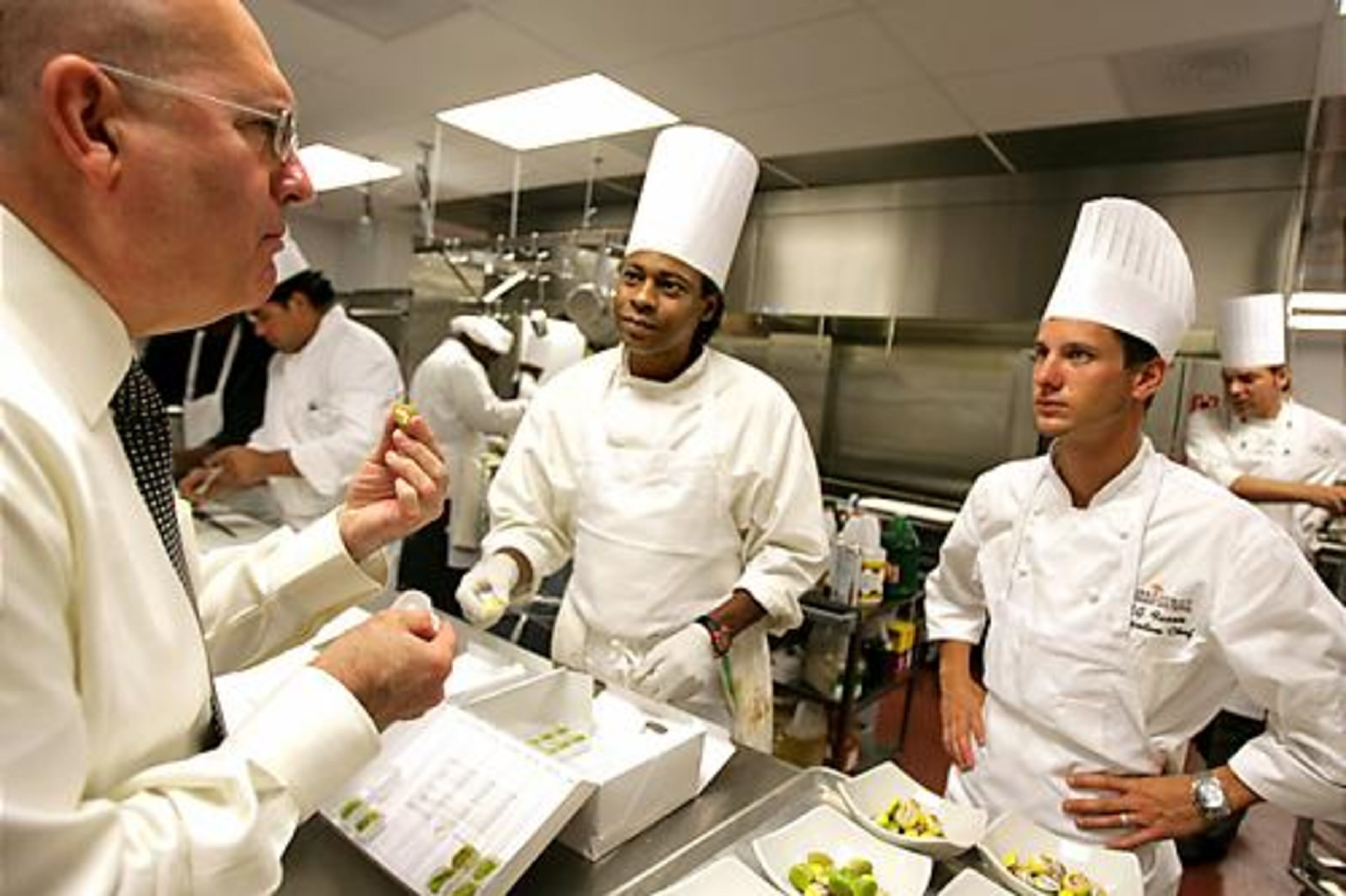 Michael Taormina (left), managing director of the Cobb Energy Performing Arts Centre, gives his compliments to Executive Chef M.G. Farris (right) after trying some of the French desserts being prepared for Saturday's opening events.