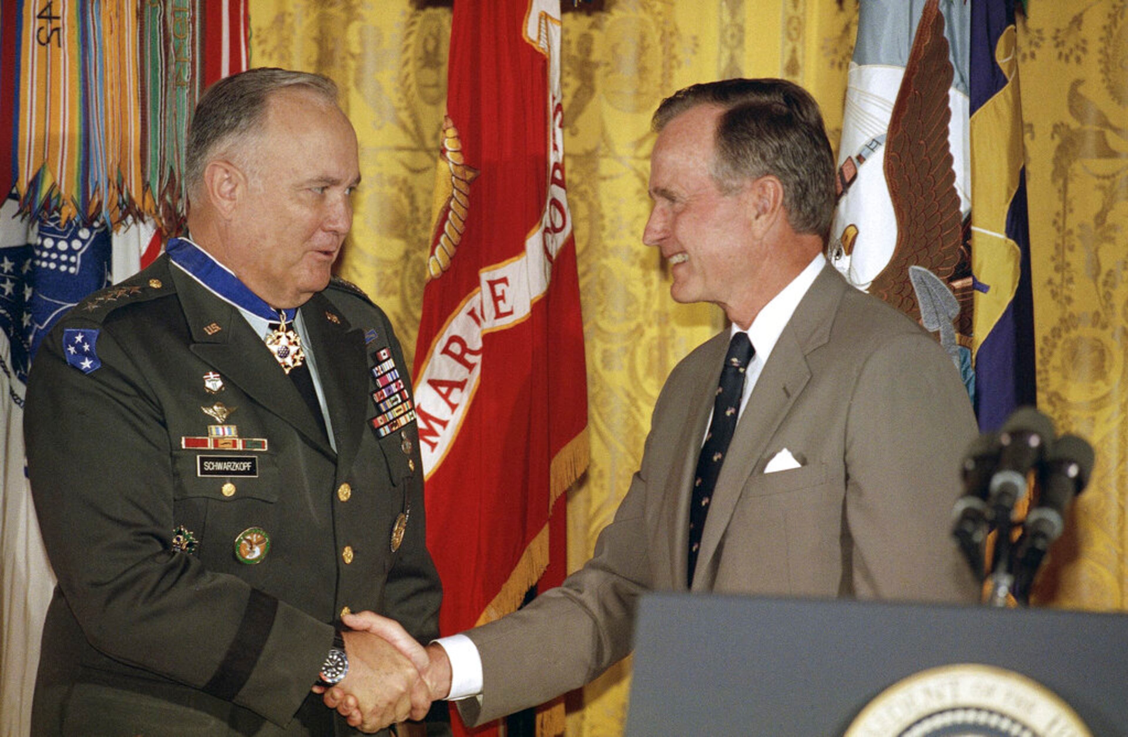 FILE - In this July 4, 1991 file photo, President George H. W. Bush congratulates Desert Storm commander Gen. Norman Schwarzkopf after presenting him with the medal of freedom at the White House in Washington. Bush also bestowed the medal on Joint Chiefs of Staff Chairman Gen. Colin Powell. (AP Photo/Doug Mills)