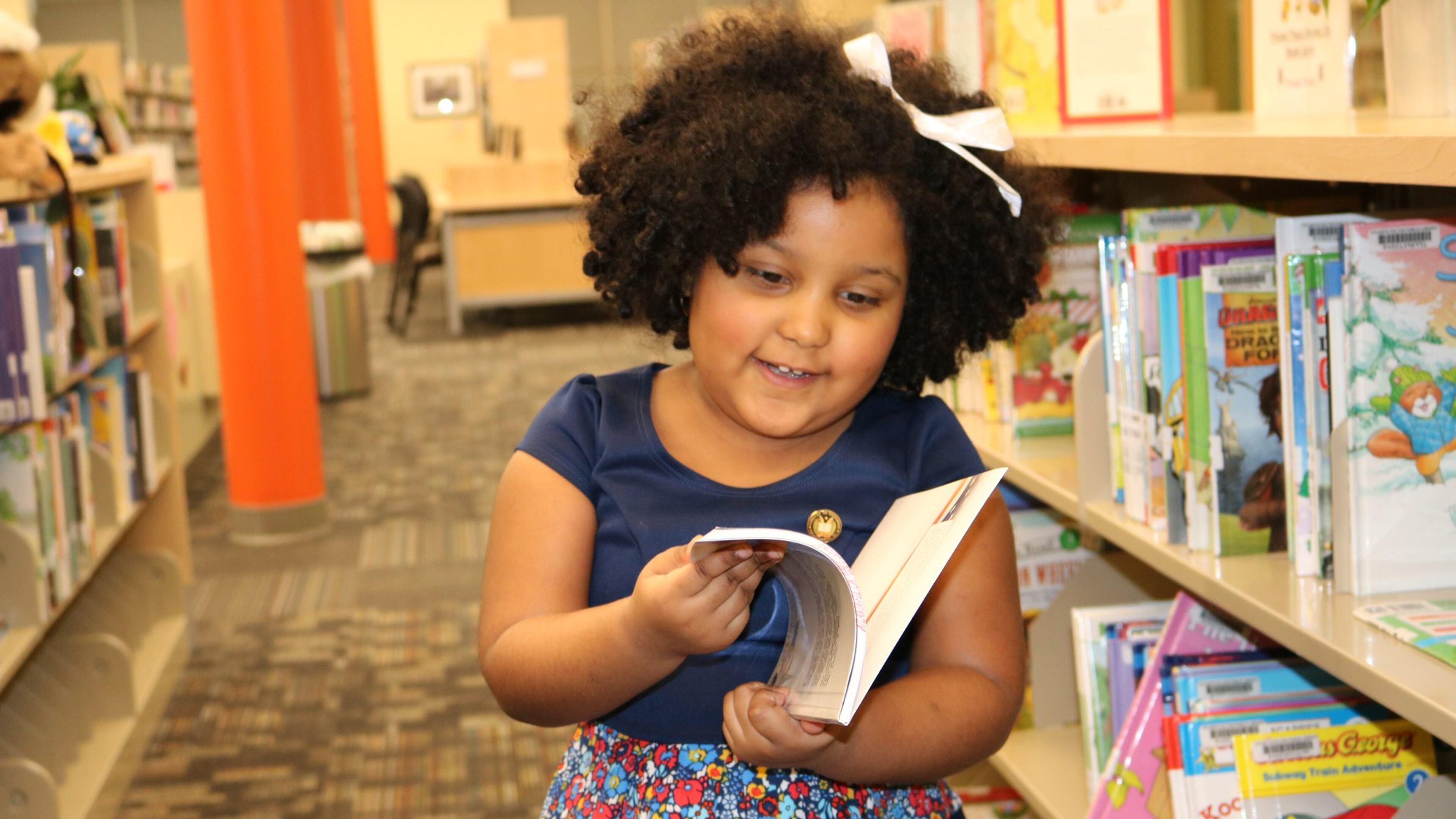 Daliyah Marie Arana of Gainesville thumbs through a book at the Southeast Atlanta Library. Daliyah, 5, has read more than 1,000 books since starting to read on her own at age 2. CONTRIBUTED BY RACHEL DANIELS / ATLANTA-FULTON PUBLIC LIBRARY SYSTEM