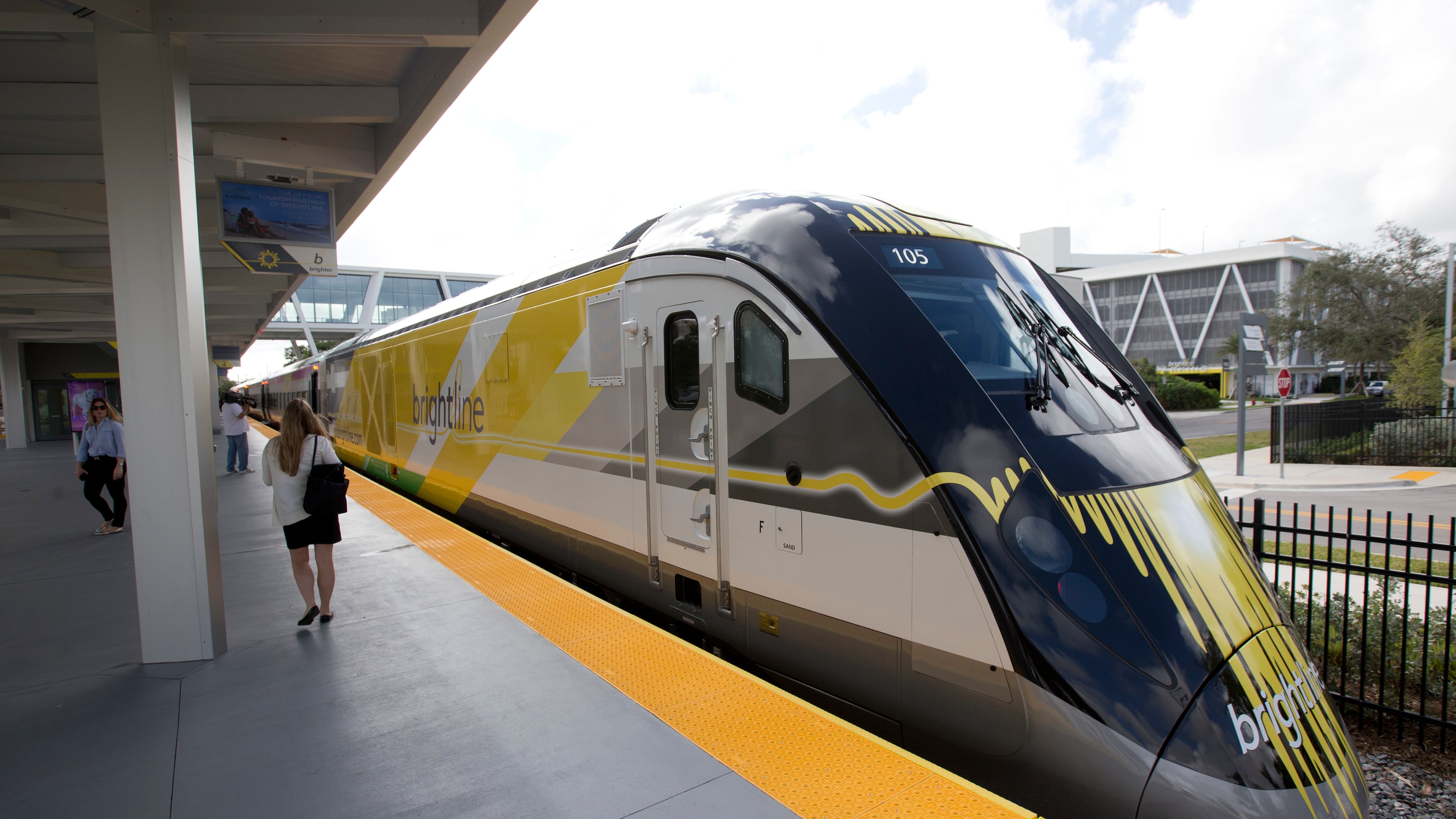 FILE -People walk near a Brightline train at a station, Jan. 11, 2018, in Fort Lauderdale, Fla. t. (AP Photo/Wilfredo Lee, File)