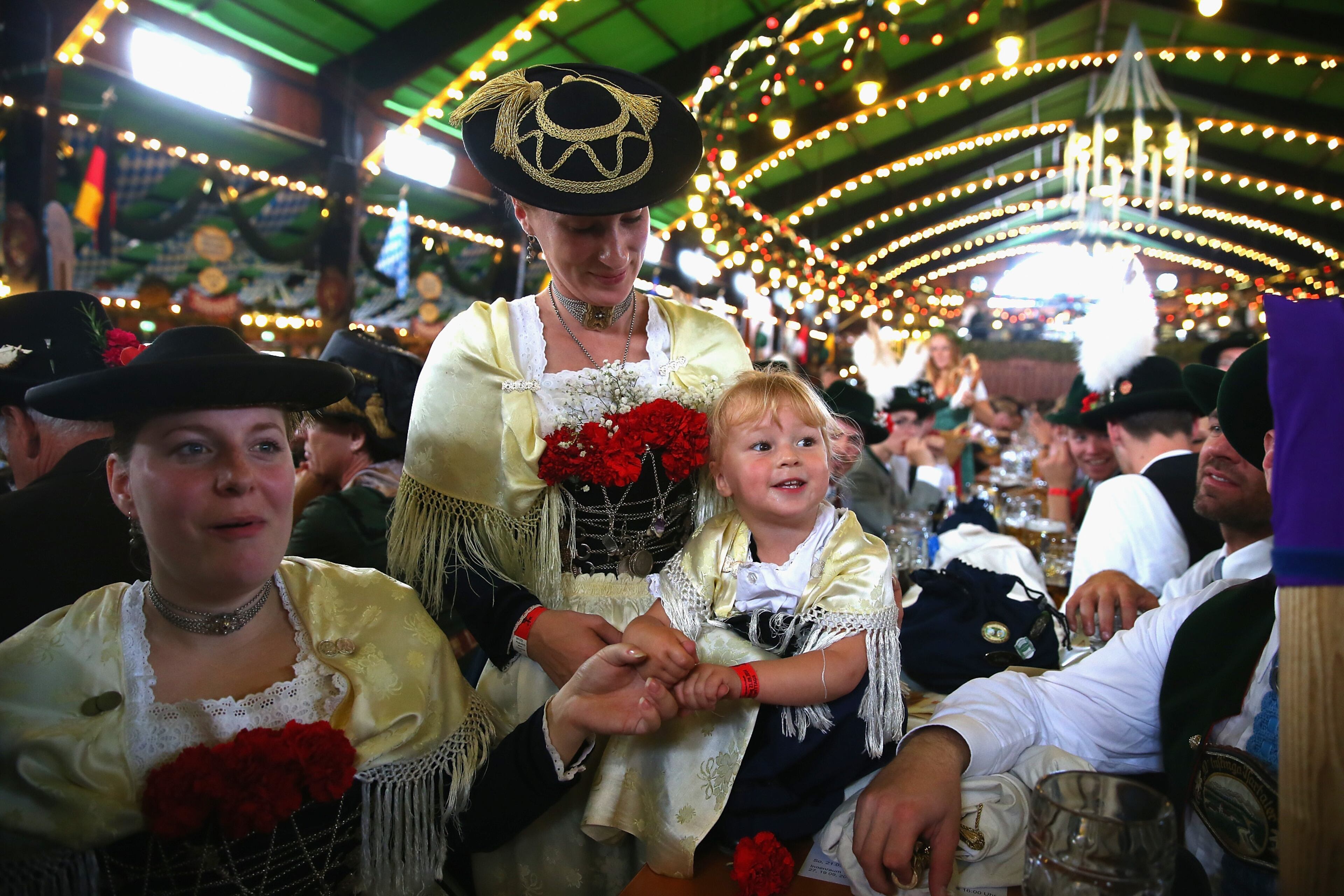 MUNICH, GERMANY - SEPTEMBER 21: The two years old Mia-Joely and her mother Marianne from the city of Trudering near Munich enjoy the atmosphaere at Augustiner Beer tent after the Parade of Costumes and Riflemen (Trachten- und Schuetzenzug) on the second day of the 2014 Oktoberfest at Theresienhoehe on September 21, 2014 in Munich, Germany. The 181st Oktoberfest will be open to the public from September 20 through October 5 and traditionally draws millions of visitors from across the globe in the world's largest beer fest. (Photo by Alexander Hassenstein/Getty Images)