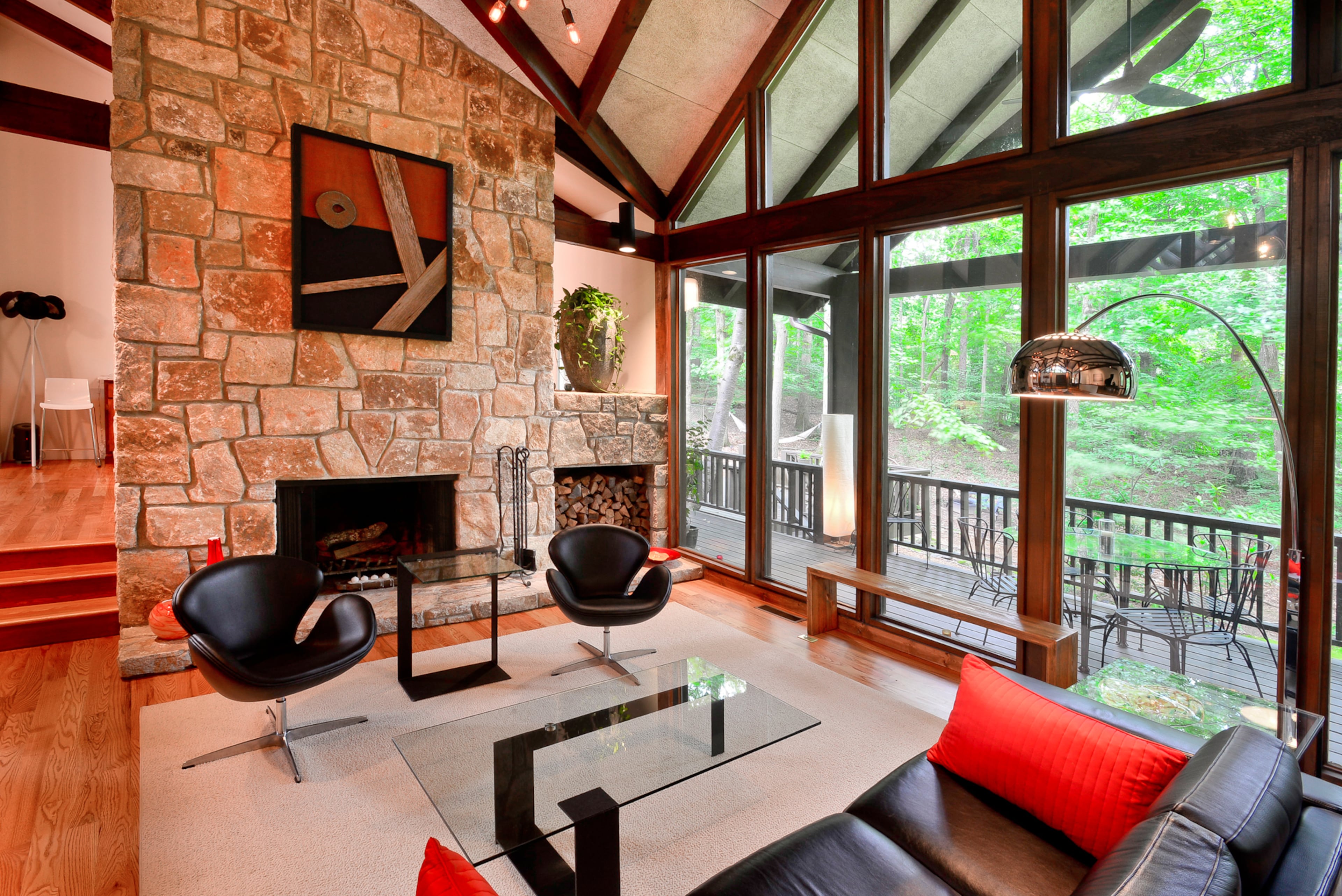 A "warm modern" interior design style fits with the contemporary architecture and use of beams throughout the home. In the living room, a glass wall looks out onto the wooded backyard, and the couple has selected classic modern furniture from stores such as Design Within Reach. The artwork is by the couple's brother in law, Rick Brown.