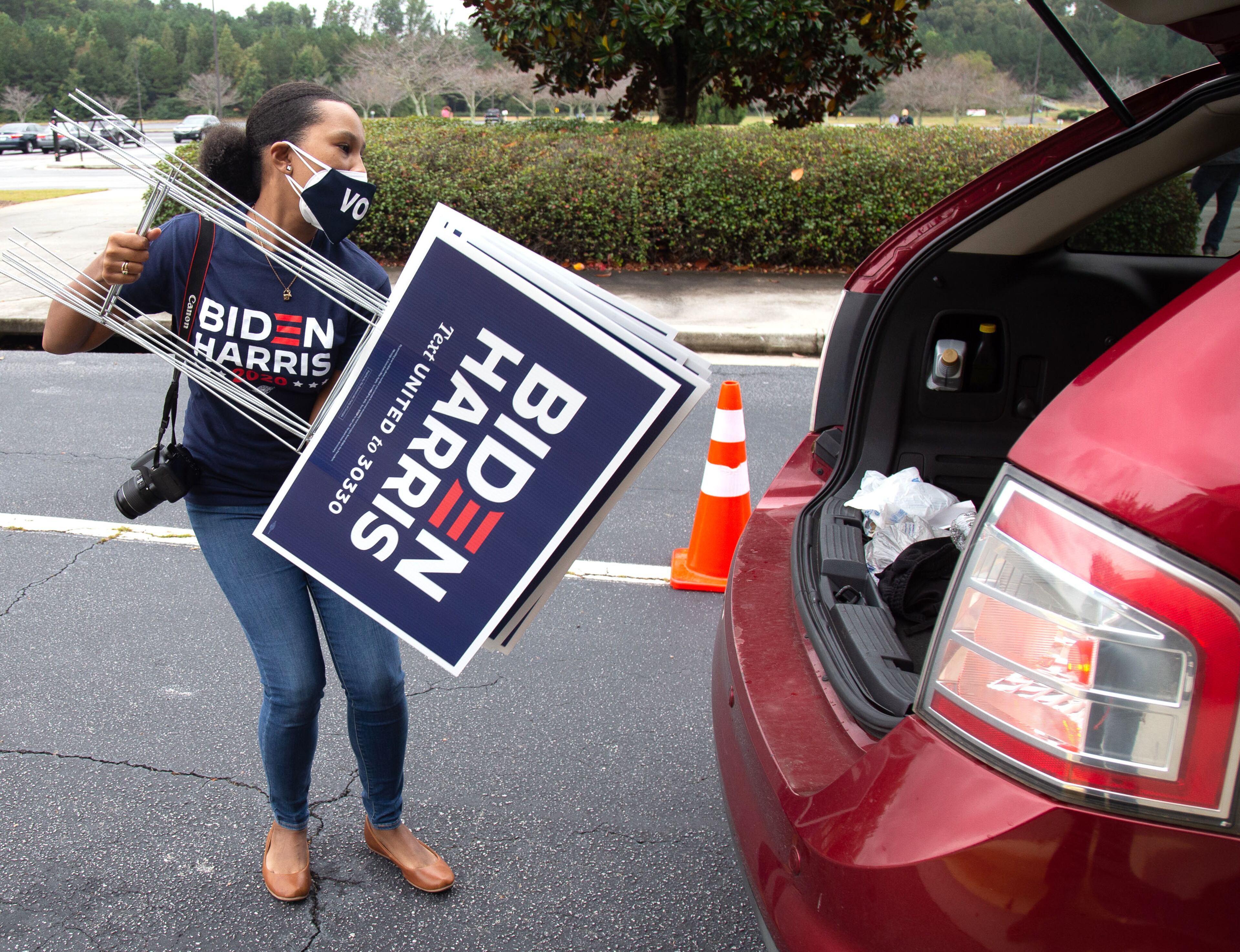 Volunteer Allison Slocum loads campaign signs into a car at a yard signs giveaway at the New Birth Missionary Baptist Church in Stonecrest Saturday, October 10, 2020. STEVE SCHAEFER / SPECIAL TO THE AJC