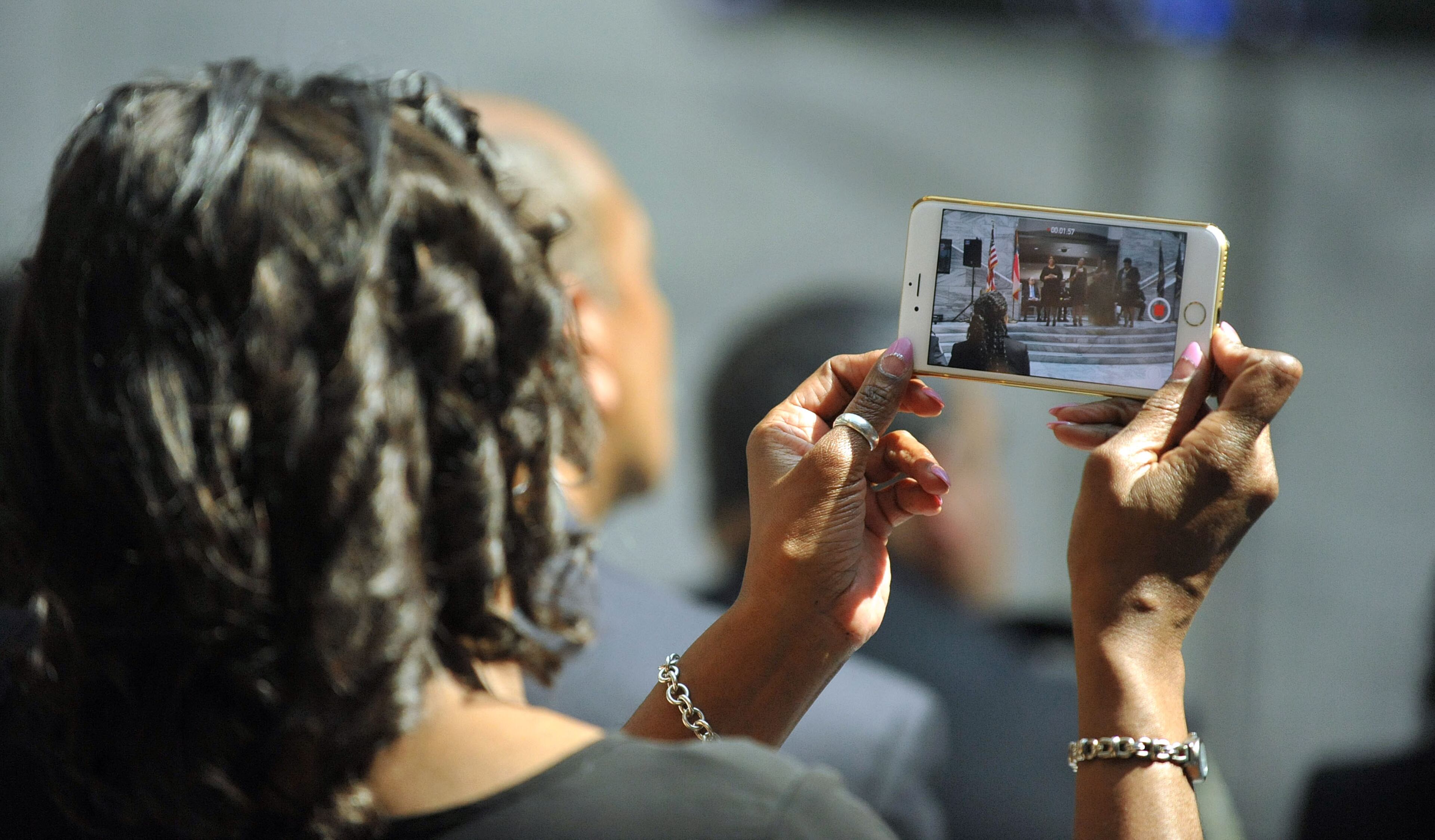 An attendee takes video during the service. KENT D. JOHNSON /KDJOHNSON@AJC.COM