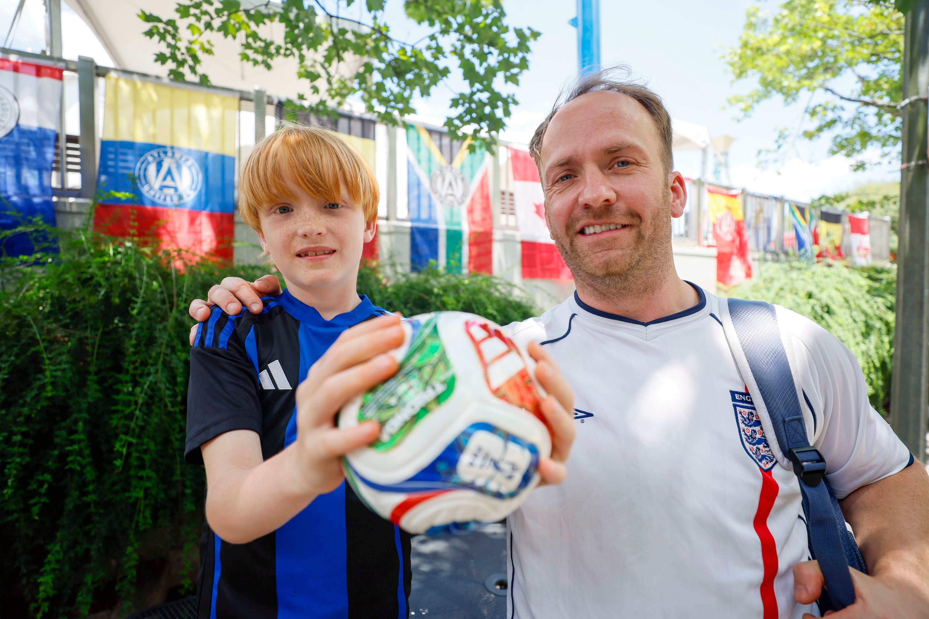 Ian Kerr and his son Sonny Kerr pose for a photo in Decatur Square, where they came to town for the World Cup round of 32 match between England and RD Congo on Monday, June 29, 2026. Ian Kerr believes that England will at least reach the quarterfinals in the knockout rounds. (Miguel Martinez/AJC)