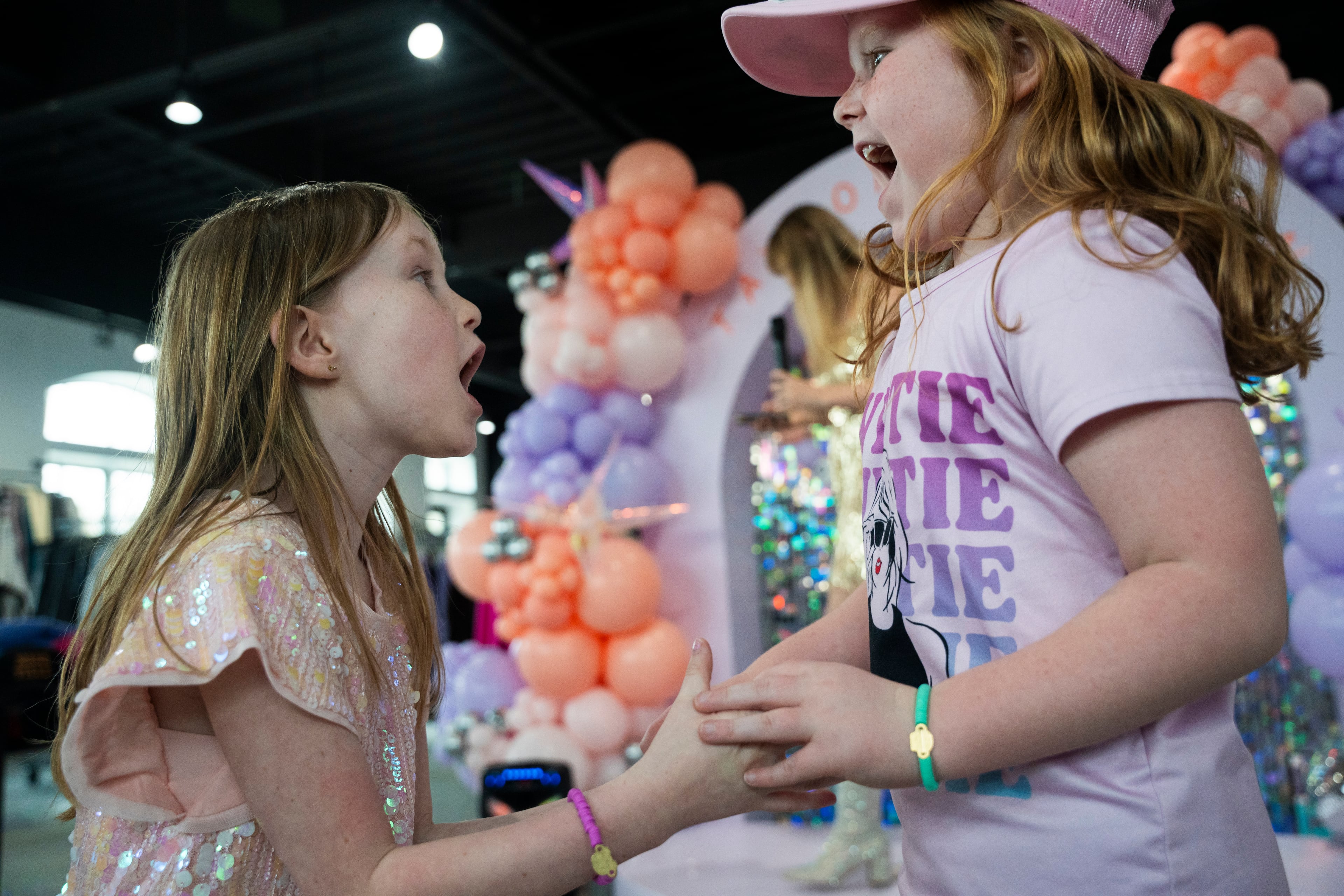 Hadley Carlson (left), and her friend Lydia Moffitt, both age 6, dance to Michelle Paget's performance as a Taylor Swift impersonator at Roxy Moxy Boutique in Cumming, Georgia, on Saturday, March 29, 2025. (Olivia Bowdoin for the AJC).