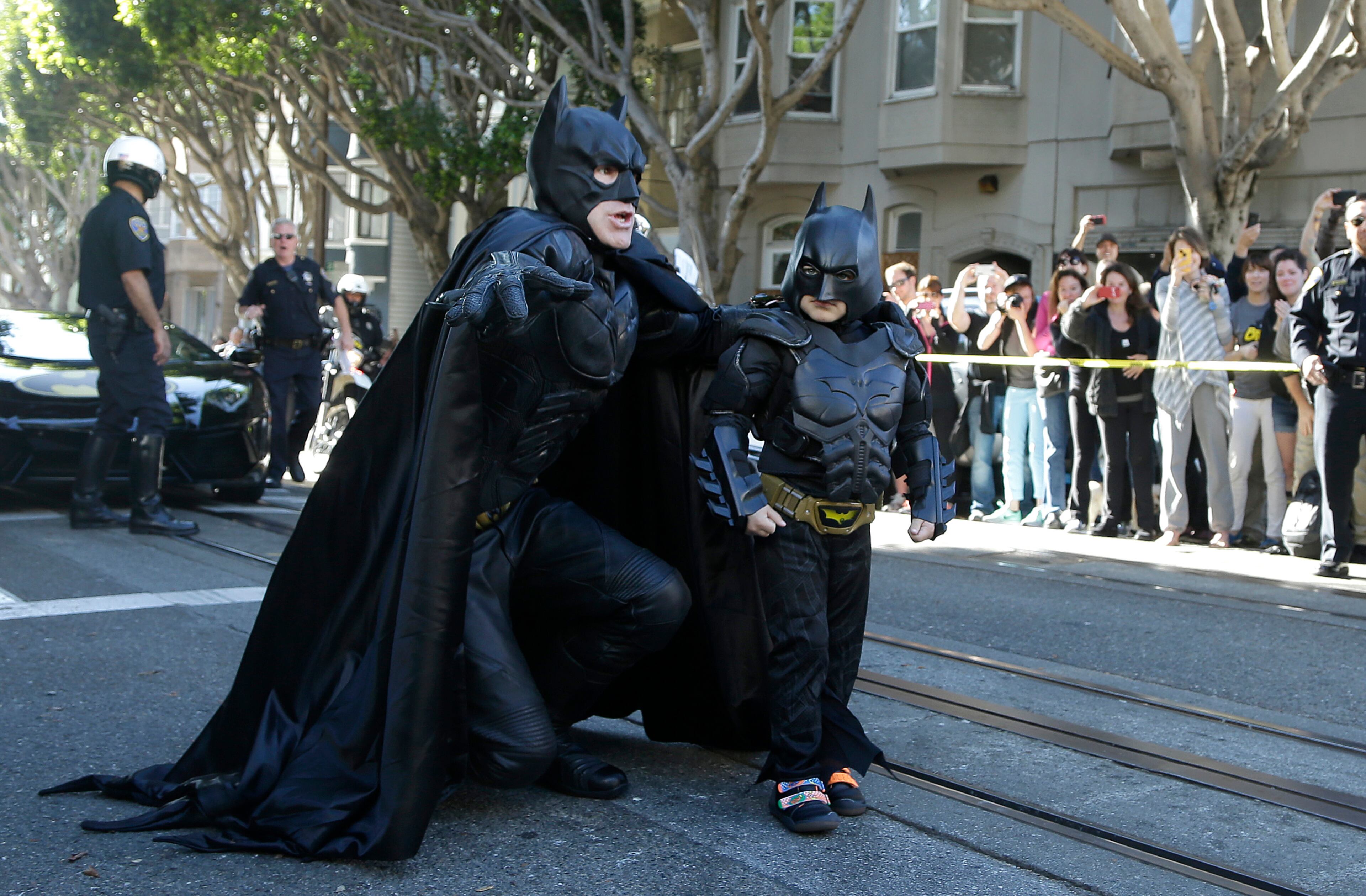 Miles Scott, dressed as Batkid, right, walks with Batman before saving a damsel in distress in San Francisco, Friday, Nov. 15, 2013. San Francisco turned into Gotham City on Friday, as city officials helped fulfill Scott's wish to be "Batkid." Scott, a leukemia patient from Tulelake in far Northern California, was called into service on Friday morning by San Francisco Police Chief Greg Suhr to help fight crime, The Greater Bay Area Make-A-Wish Foundation says.