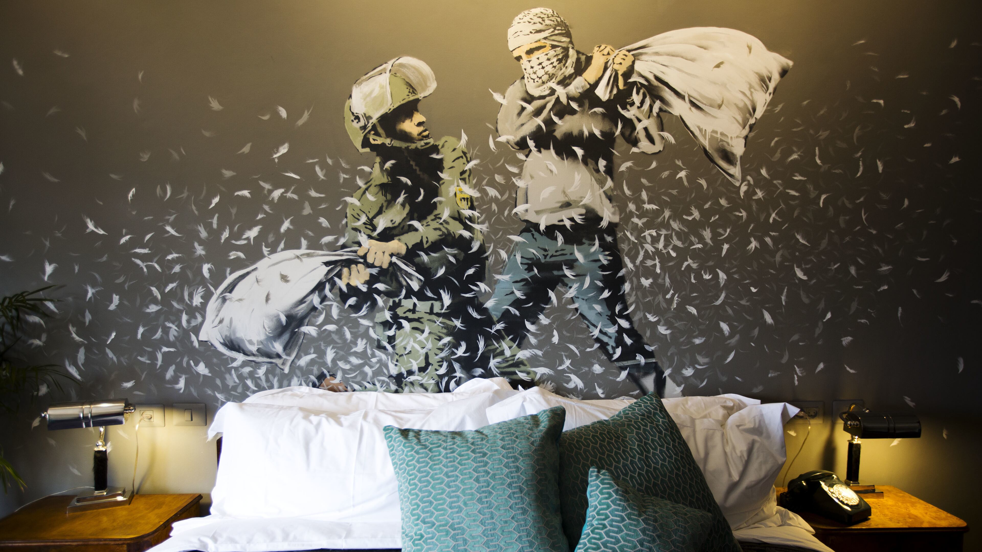 A Banksy wall painting showing Israeli border policeman and Palestinian in a pillow fight is seen in one of the rooms of the "The Walled Off Hotel" in the West Bank city of Bethlehem, Friday, March 3, 2017. The owner of a guest house packed with the elusive artist Banksy's work has opened the doors of his West Bank establishments to media, showcasing its unique "worst view in the world." The nine-room hotel named "The Walled Off Hotel" will officially open on March 11. (AP Photo/Dusan Vranic)
