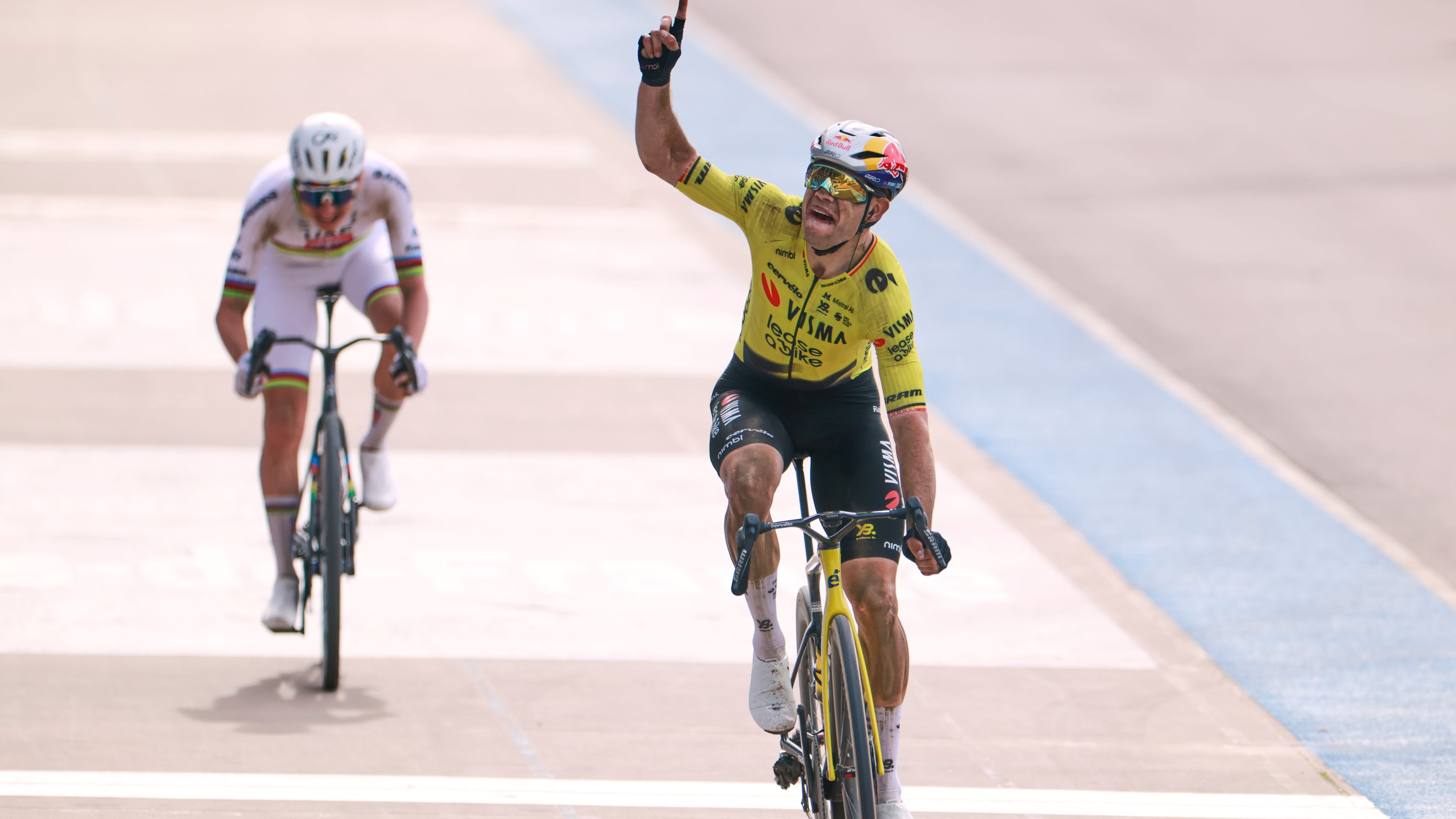 Belgium's Wout van Aert crosses the finish line ahead of Tadej Pogacar of Slovenia, left, to win the Paris-Roubaix cycling race in Roubaix, France, Sunday, April 12, 2026. Van Aert pointed his finger skywards to commemorate Belgian cyclist Michael Goolaerts who died after crashing in the race in 2018. (AP Photo/Jean-Francois Badias)