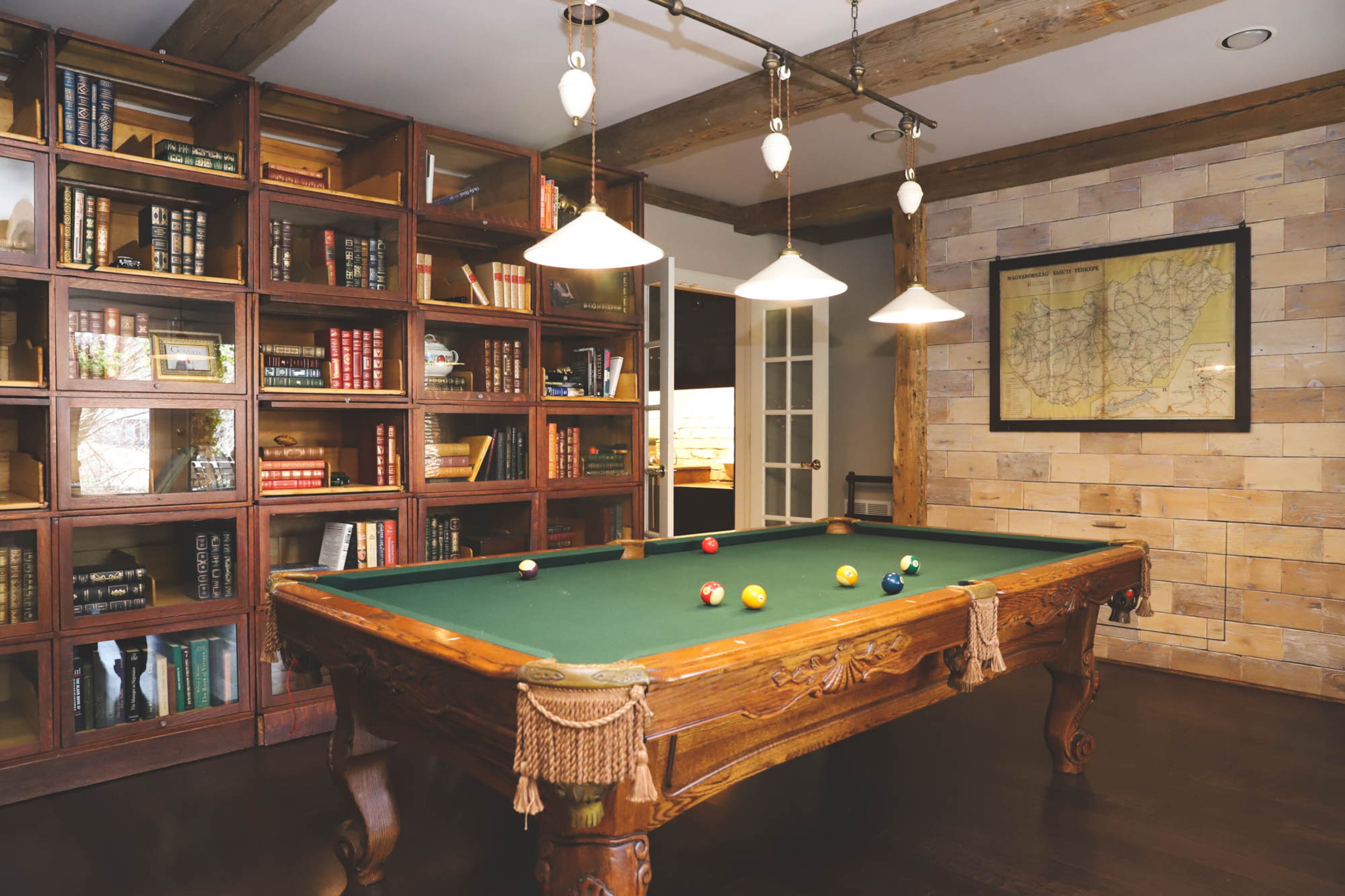 The pool table room in the basement of Joe and Stacy Borocz’s Roswell home has a more English club style than the main floor. Reclaimed oak beams from a turn-of-the-century building in Europe run along the ceiling, and vintage shelves from a millinery shop in Louisville, Kentucky, serve as bookcases that house Joe’s collection of leather bound books. Text by Shannon Dominy/Photo by Reynolds Rogers