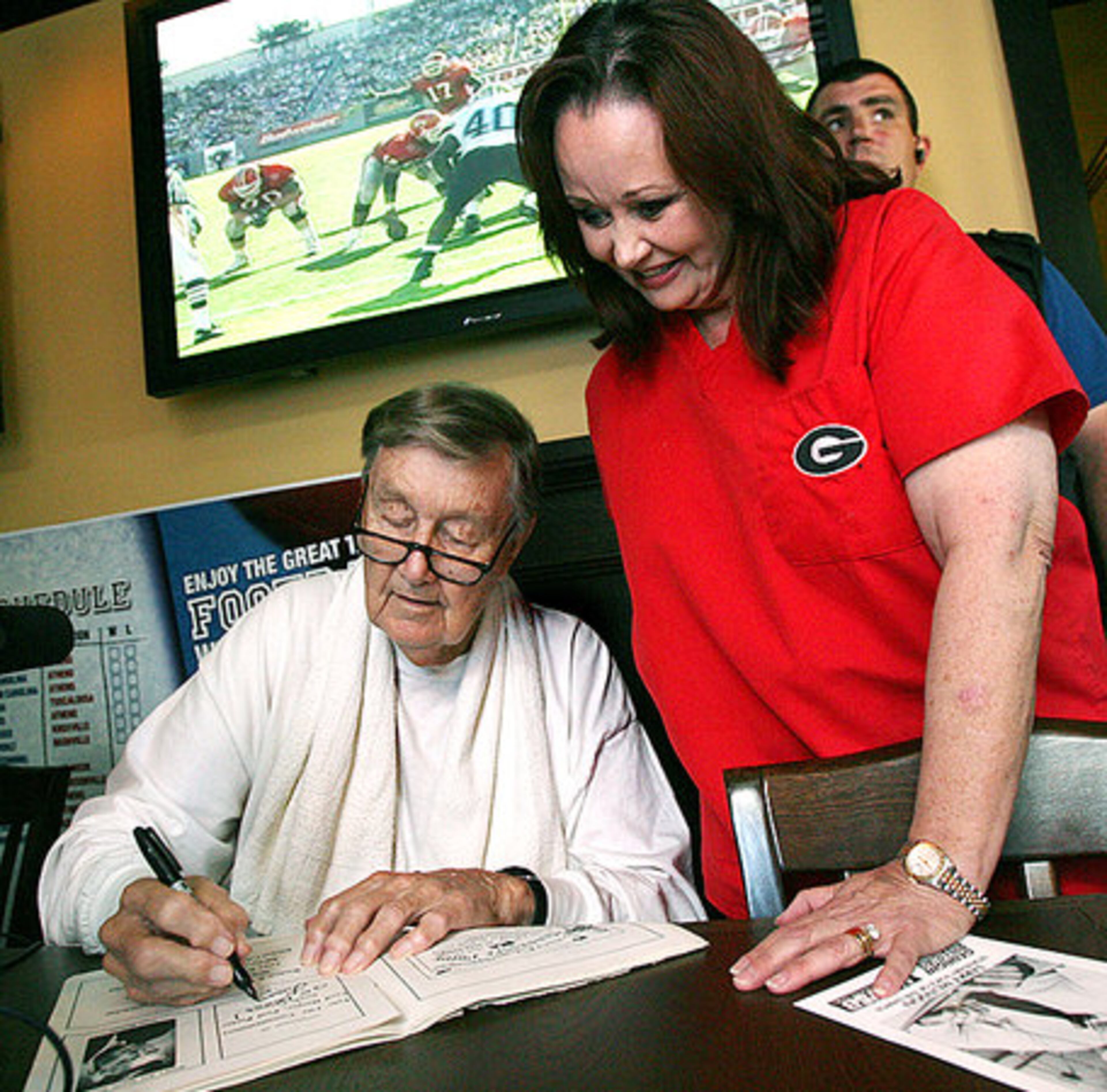 Munson, here signing an autograph for Linda Hicks, said he never contrived any of the calls that endeared him to Georgia fans. "I didn't plan any of that stuff. It just came out. I was just calling what I saw and what I felt."