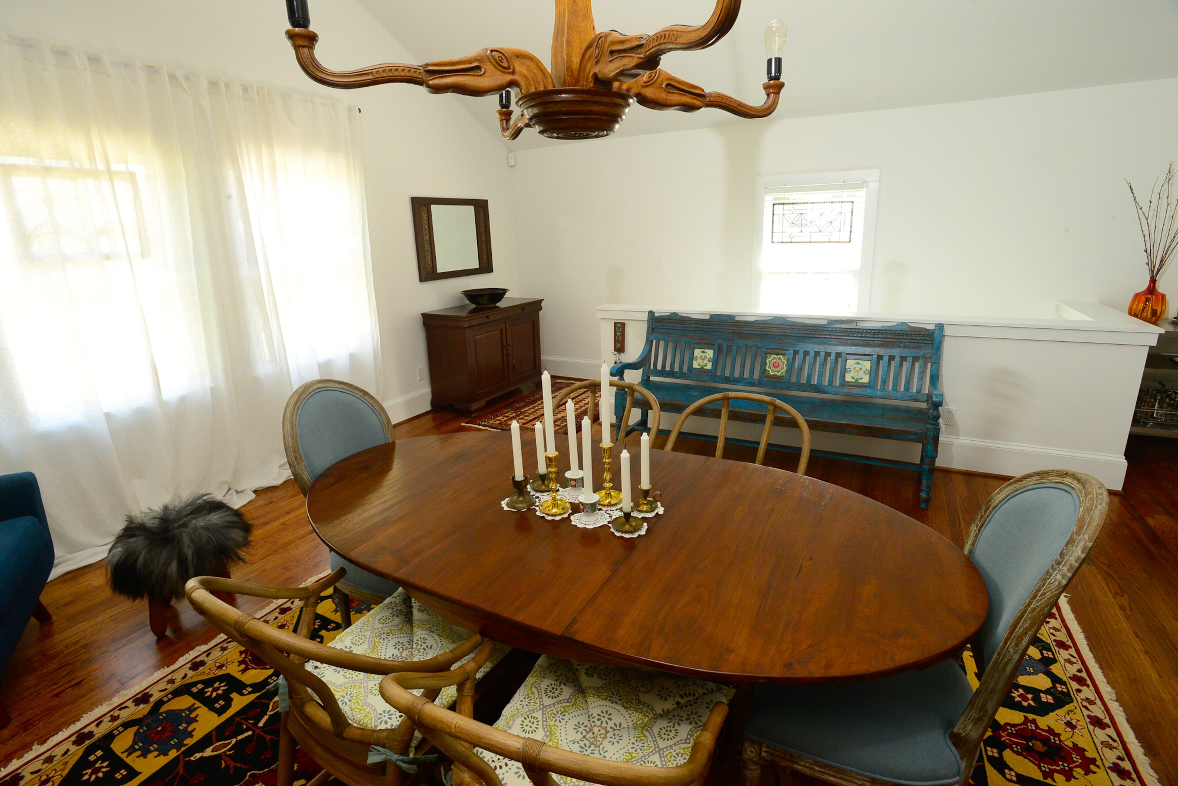 A teak dining table from Manorism is situated on a handmade Turkish rug from World of Rugs in the dining room. Other international items are the antique Indian bench and Belgian chandelier.