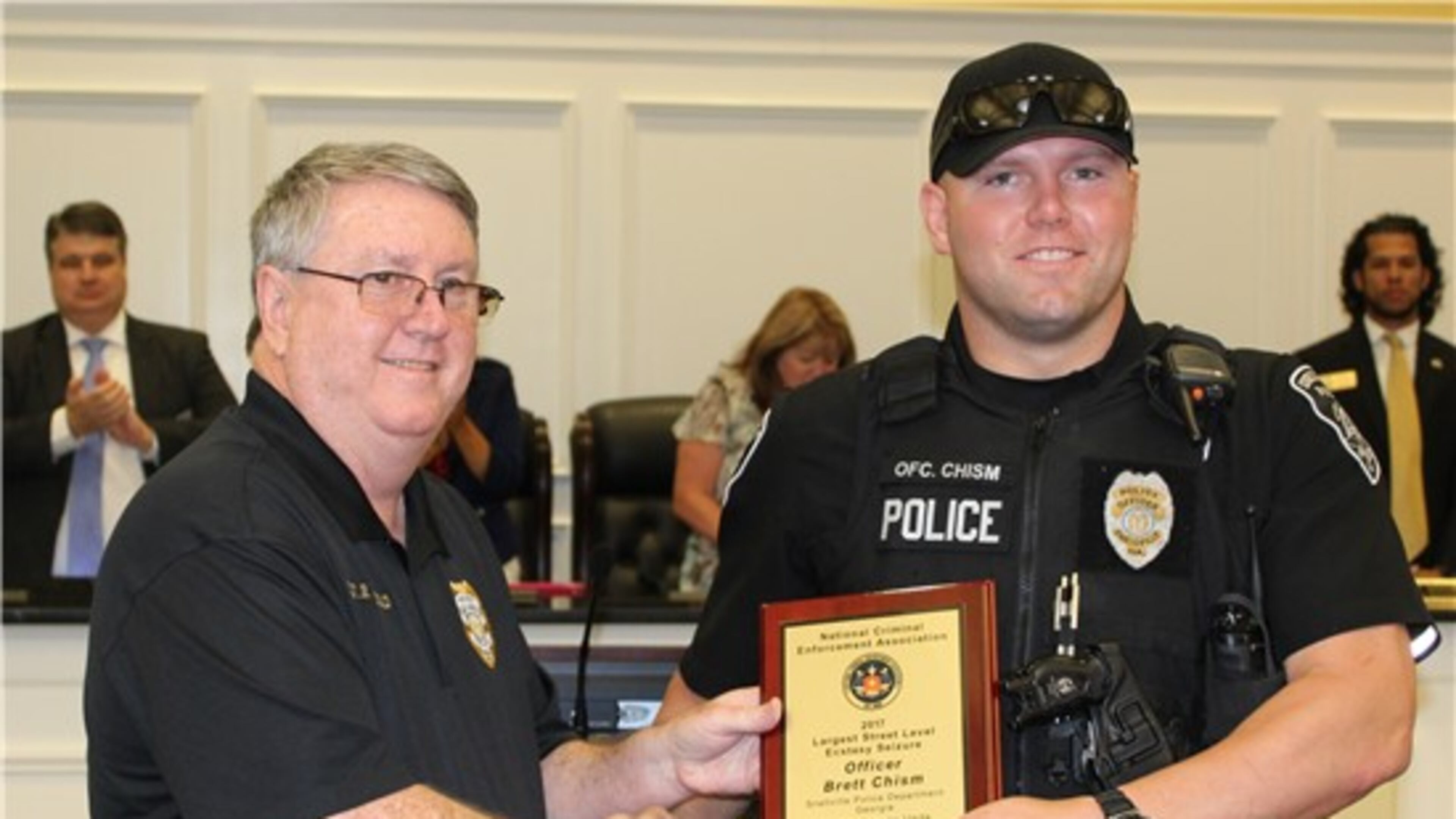 From left, Snellville Police Department Chief Roy Whitehead presents officer Brett Chism with the National Criminal Enforcement Association award for making a bust of 45,000 ecstasy pills at Monday’s Council meeting. Courtesy Snellville
