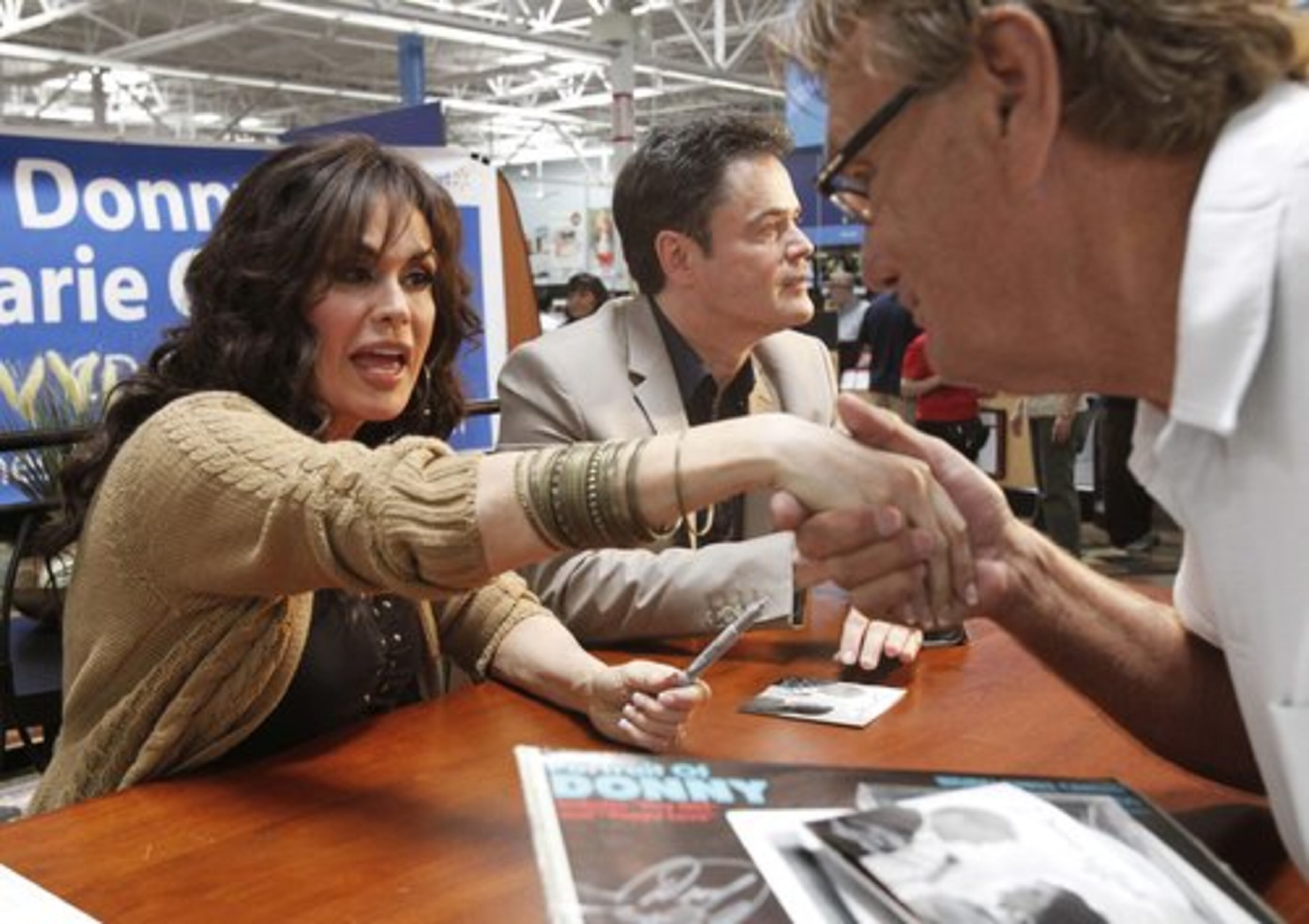 ATTENTION WALMART SHOPPERS, THE DONNY & MARIE CD DOES NOT INCLUDE MARIE'S HAND: William Triem, from Peoria, Ariz., kisses the hand of performer Marie Osmond, left, as she and her brother Donny Osmond, appear at a signing for, "Donny & Marie, " their first album in 30 years, at Walmart in Mesa, Ariz. on Wednesday, May 11, 2011.
