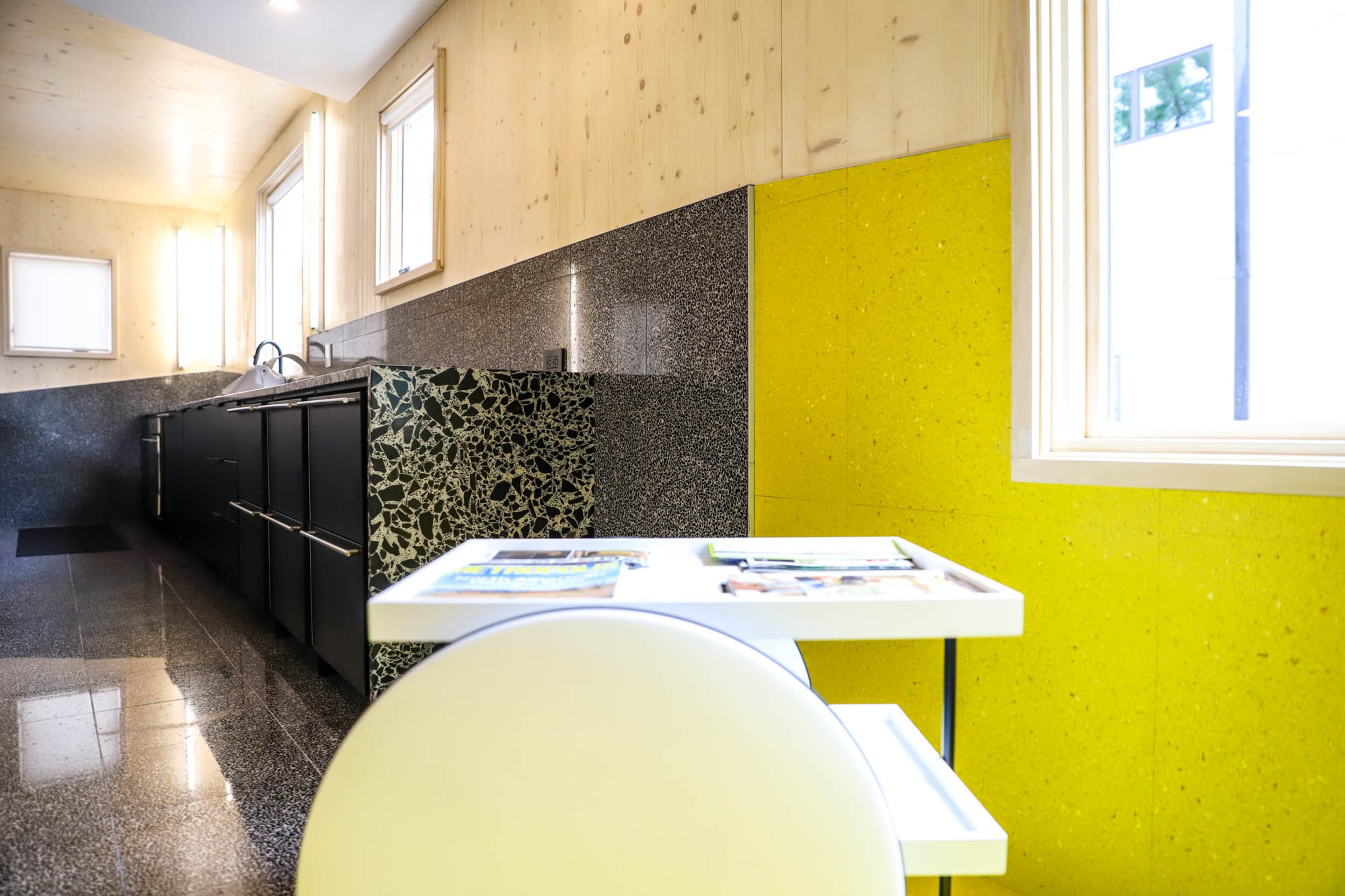 Yellow vinyl marble and black terrazzo appear as wainscoting in the contemporary home. Casamania's Chariot mobile table is designed by Stine Gam and Enrico Fratesi with GamFratesi Studio.