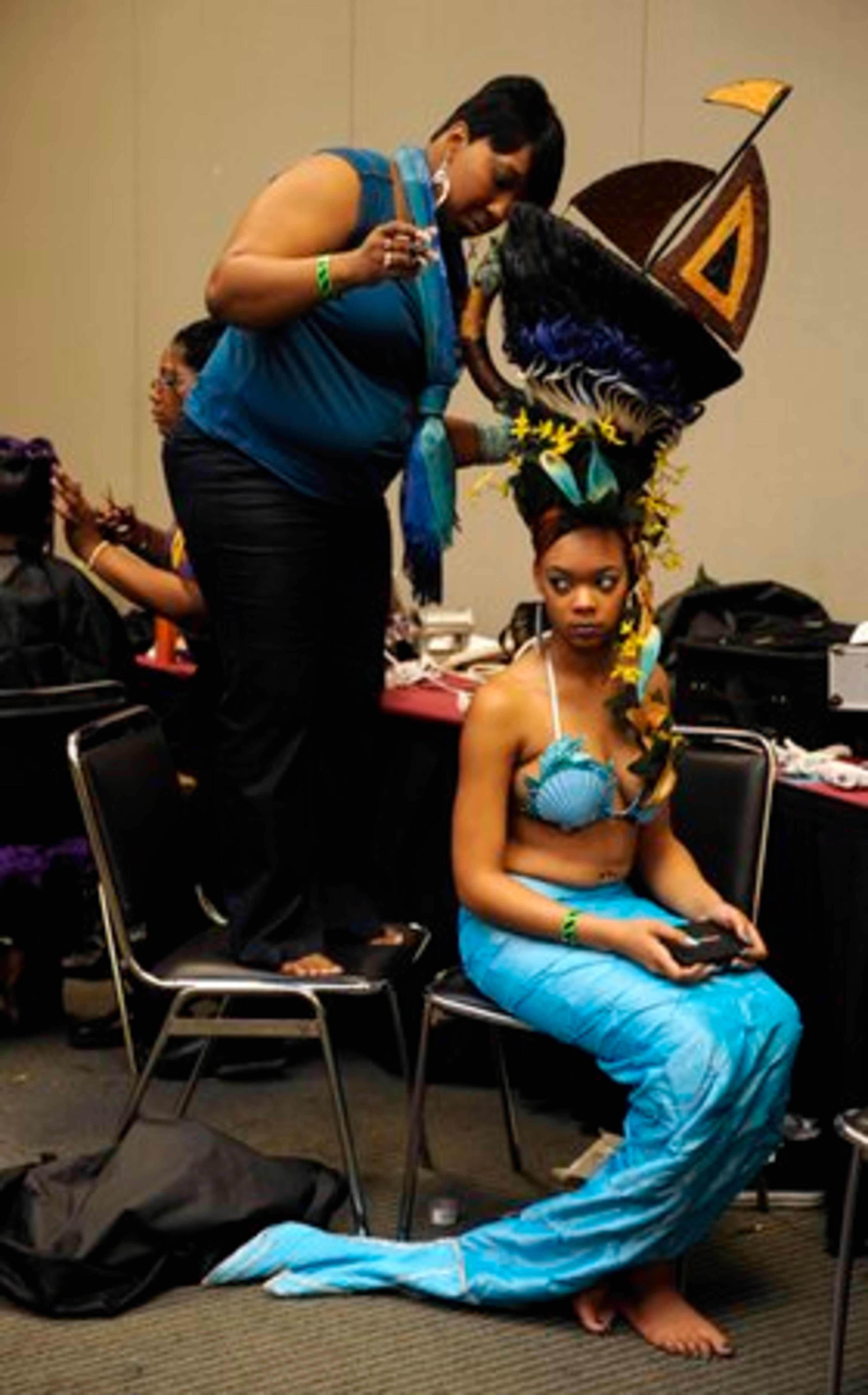 From left, Stylist Veronica Kimmons, 27, of Holly Springs, Miss., steadies herself on a chair in order to complete her goddess of the sea fantasy look on model Twyla Mays, 20.