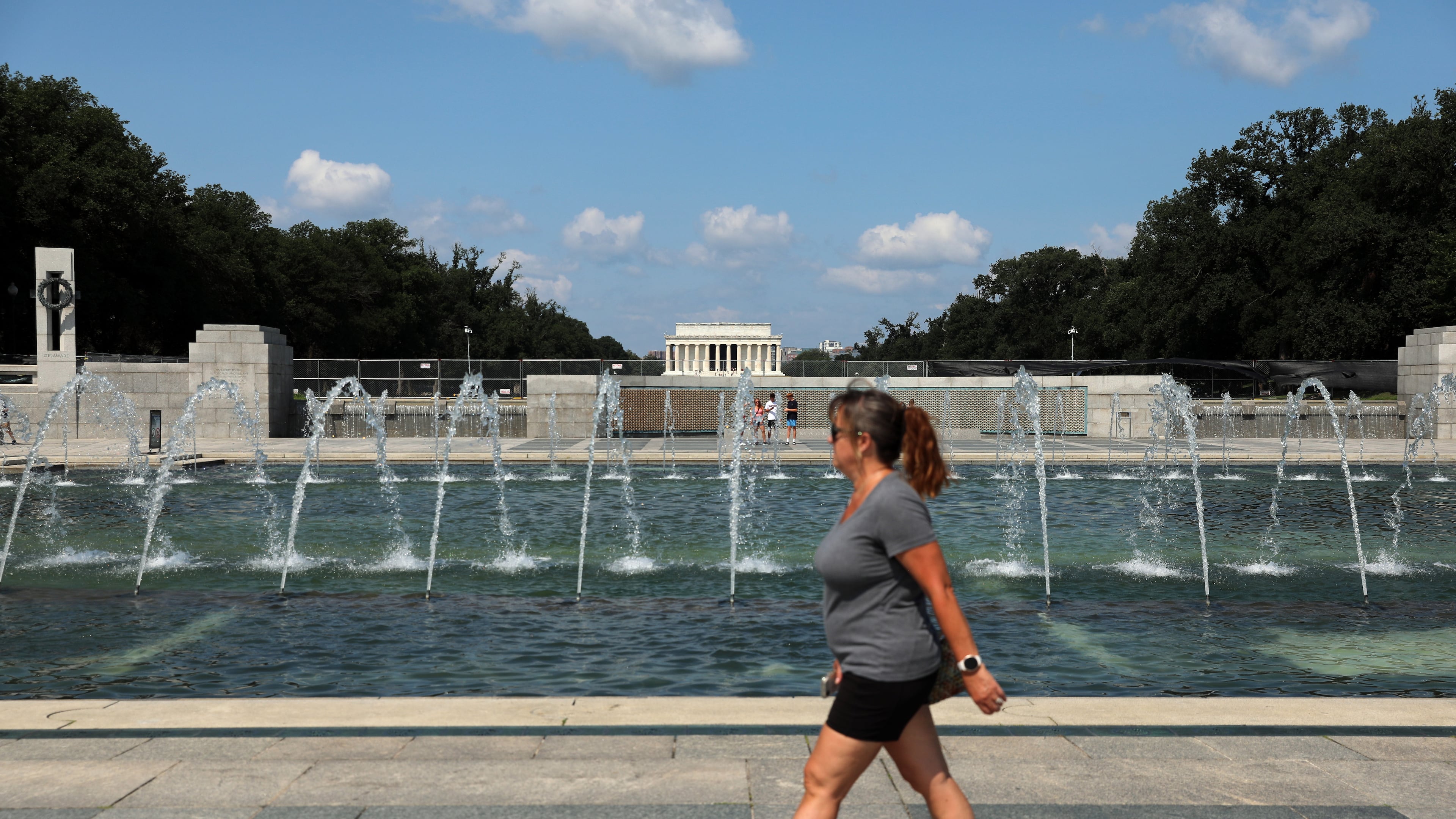A woman walks near the fountain at the WWII Memorial, in Washington, Wednesday, July 29, 2026. (AP Photo/Rahmat Gul)
