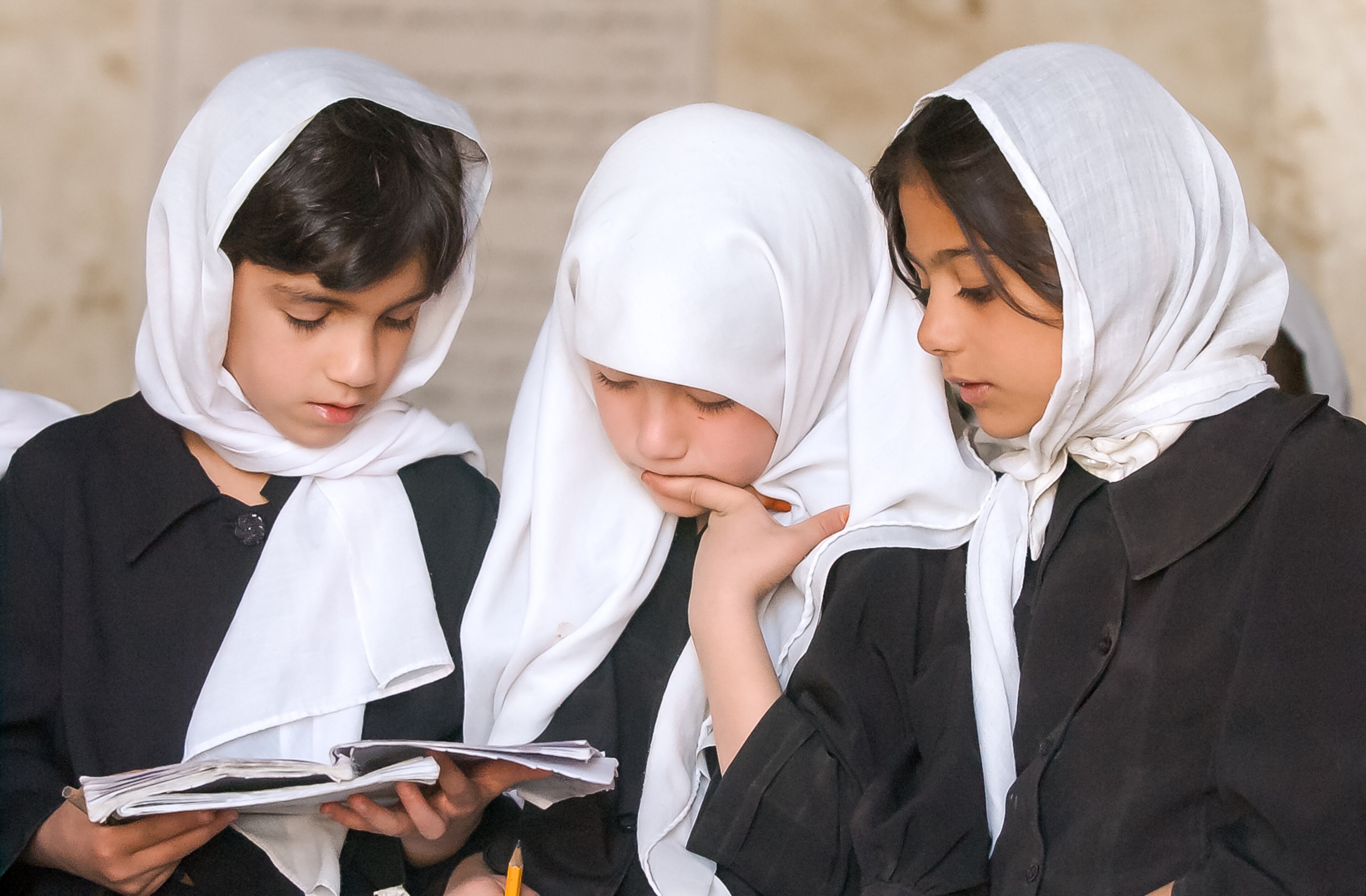 KABUL, AFGHANISTAN: From left, third-graders Tamana Tellaee, 7, Mariam, 8, and Nellab, 8, share a book as they review Dari lessons with their class at the Naswan Manochary girls' school in Kabul Sunday, Sept. 15, 2002. (Bita Honarvar / The Atlanta Journal-Constitution)