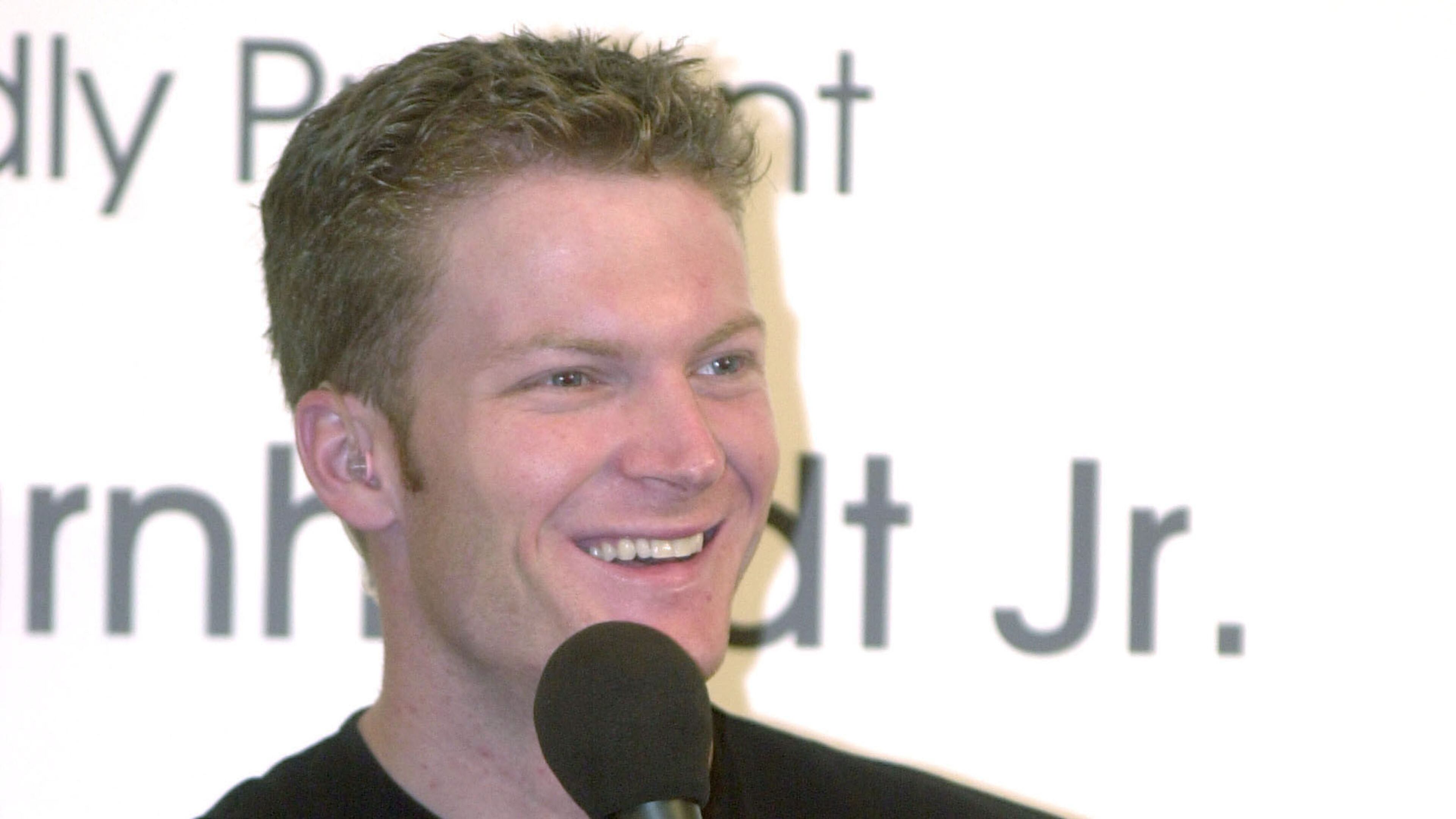 NEW YORK - AUGUST 8: Race car driver Dale Earnhardt, Jr. answers fan questions before the start of the Drakkar Noir pit crew challenge between New York City Police officers and firefighters August 8, 2002 in New York City. The charity event raised $25,000 for the New York Police and Firefighters Widows and Children's Benefit Fund. (Photo by Getty Images)