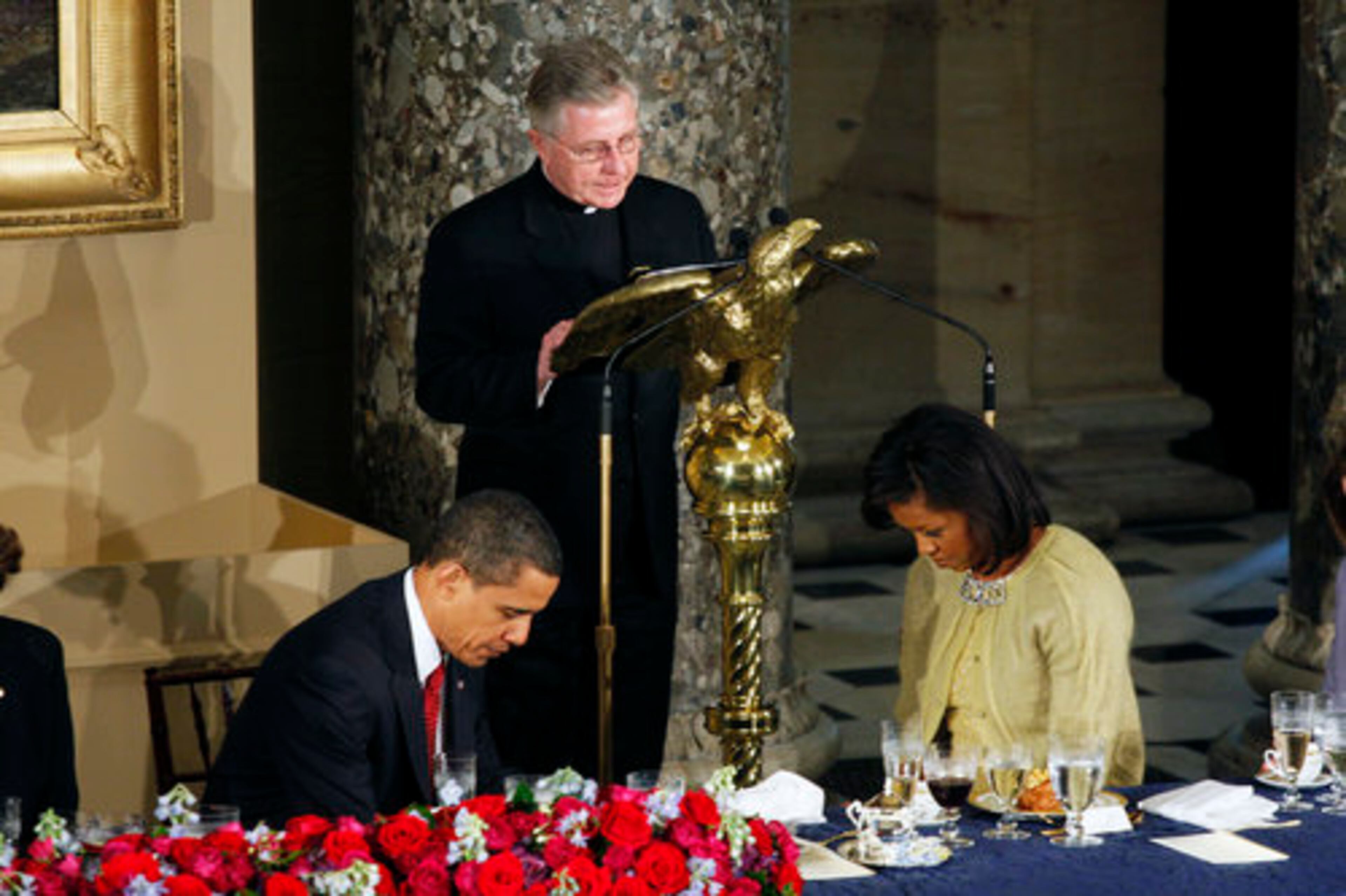 President Barack Obama and First Lady Michelle Obama bow during the ending prayer recited by House of Representatives Chaplin Daniel Coughlin in Statutory Hall at the U.S. Capitol.