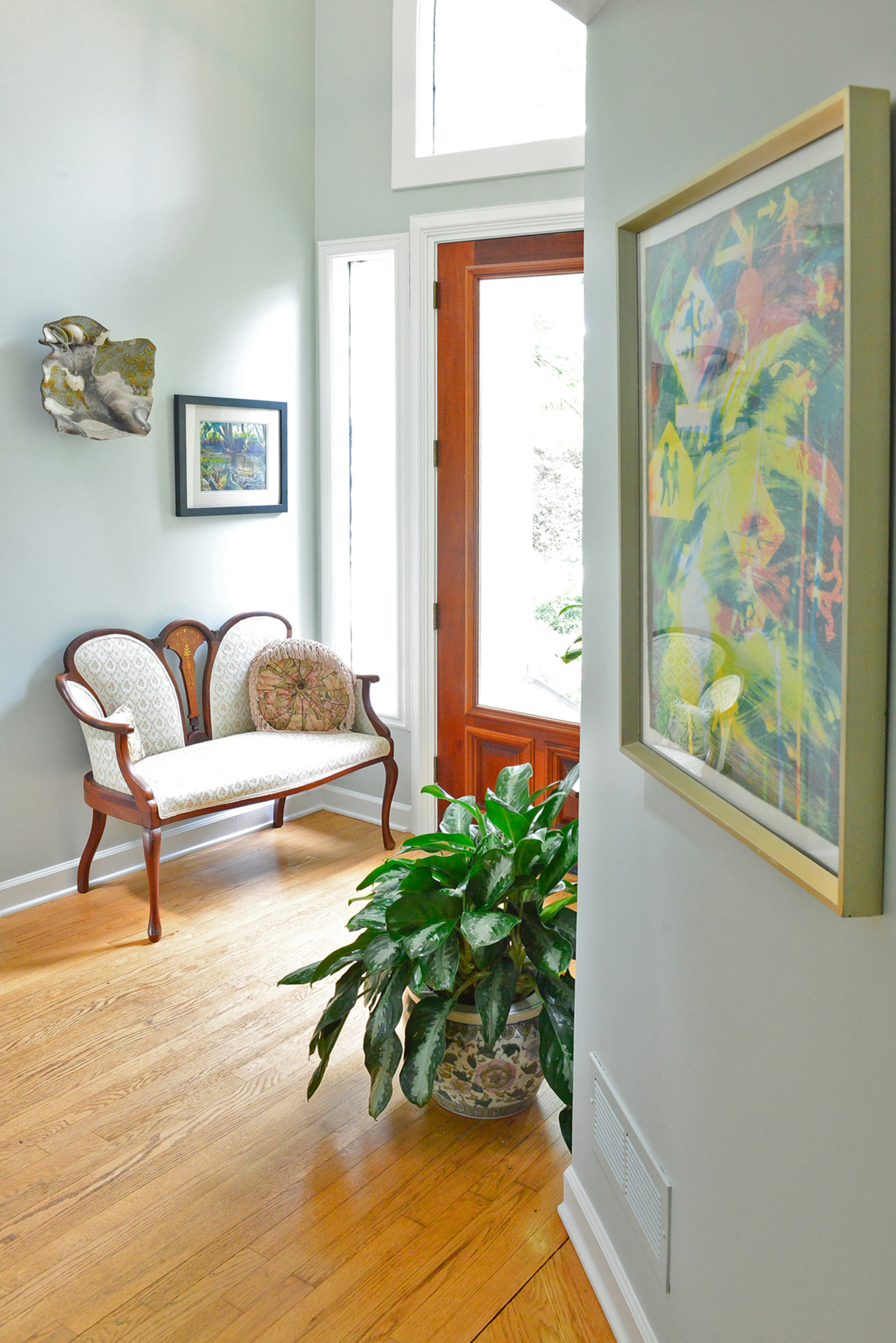 Modern artwork and an antique rosewood couch inlaid with walnut and mahogany are bathed in light in the entryway. The art reflects the unique home's decidedly modern design, while the heirloom furniture is a tribute to homeowner Judy Mozen's family ties. When she inherited her mother's and grandmother's furniture, Judy found a creative way to mix her modern style with the beautiful, sentimental pieces of her past.
