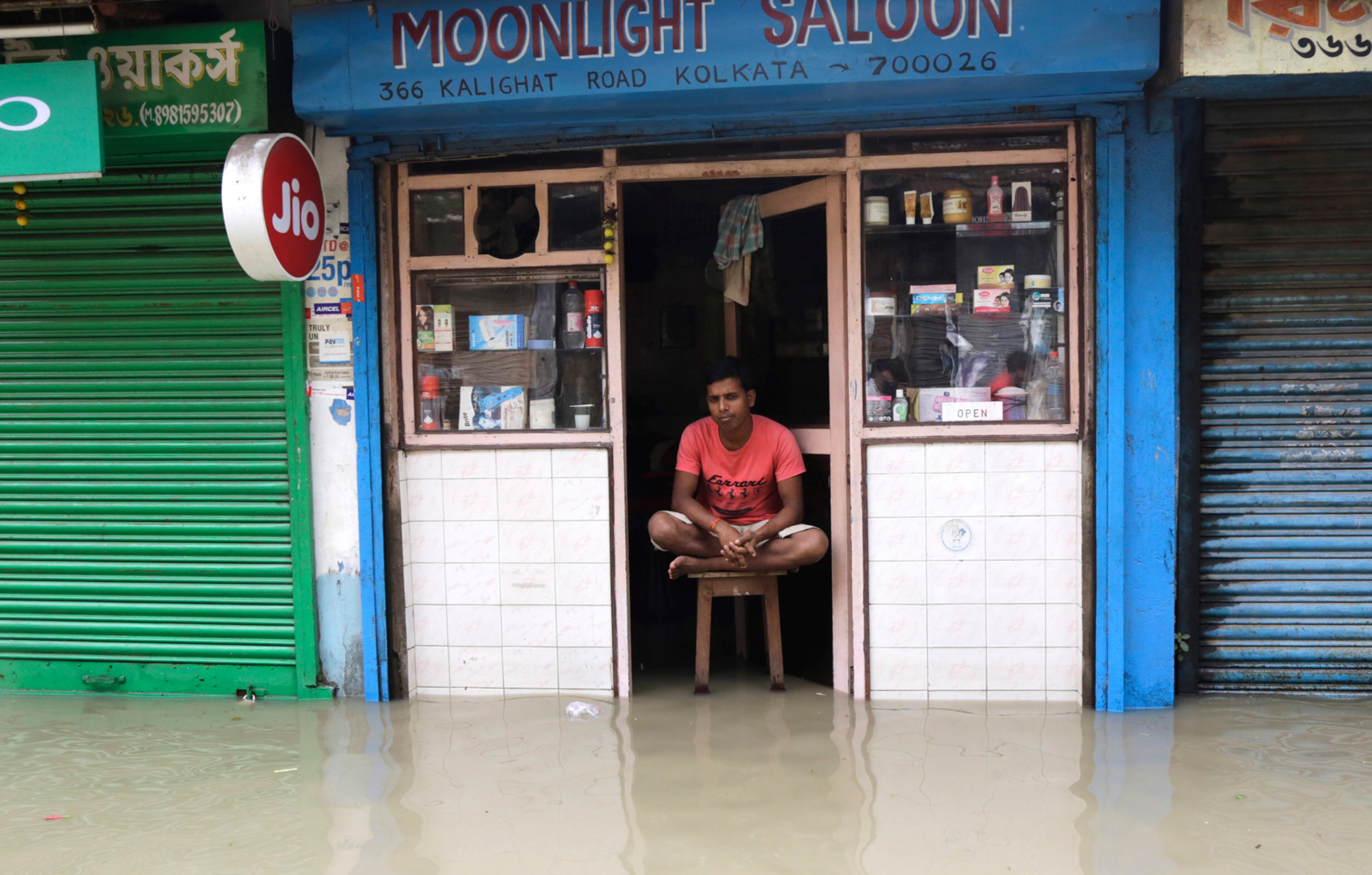 An Indian barber sits on a stool waiting for customers inside his shop on a flooded street following monsoon rains in Kolkata, India, Tuesday, July 25, 2017. The monsoon season in India runs from June to September. (AP Photo/Bikas Das)