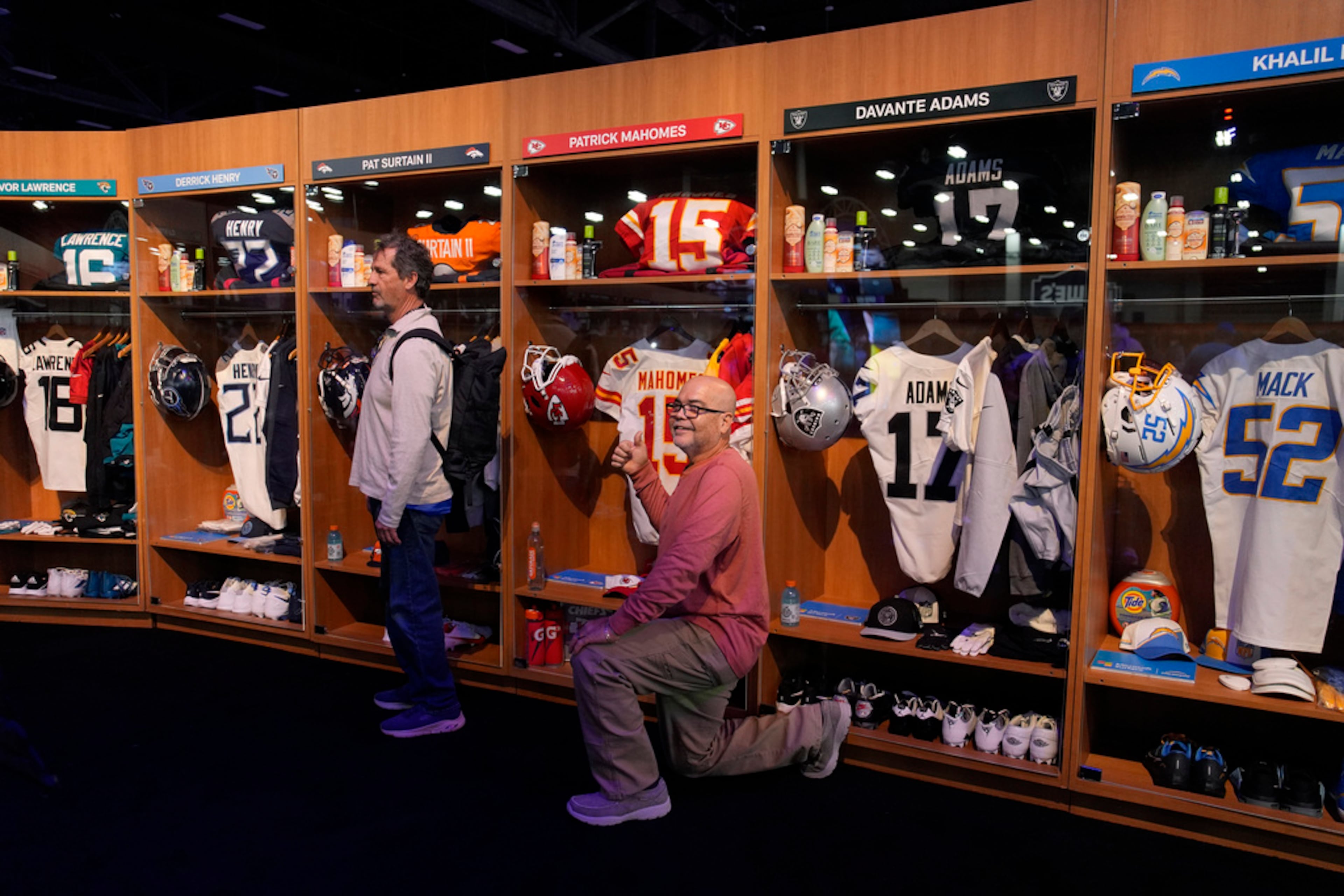 People pose for photos at a locker room exhibit at the Super Bowl Experience ahead of the Super Bowl 58 NFL football game Wednesday, Feb. 7, 2024, in Las Vegas. (AP Photo/John Locher)