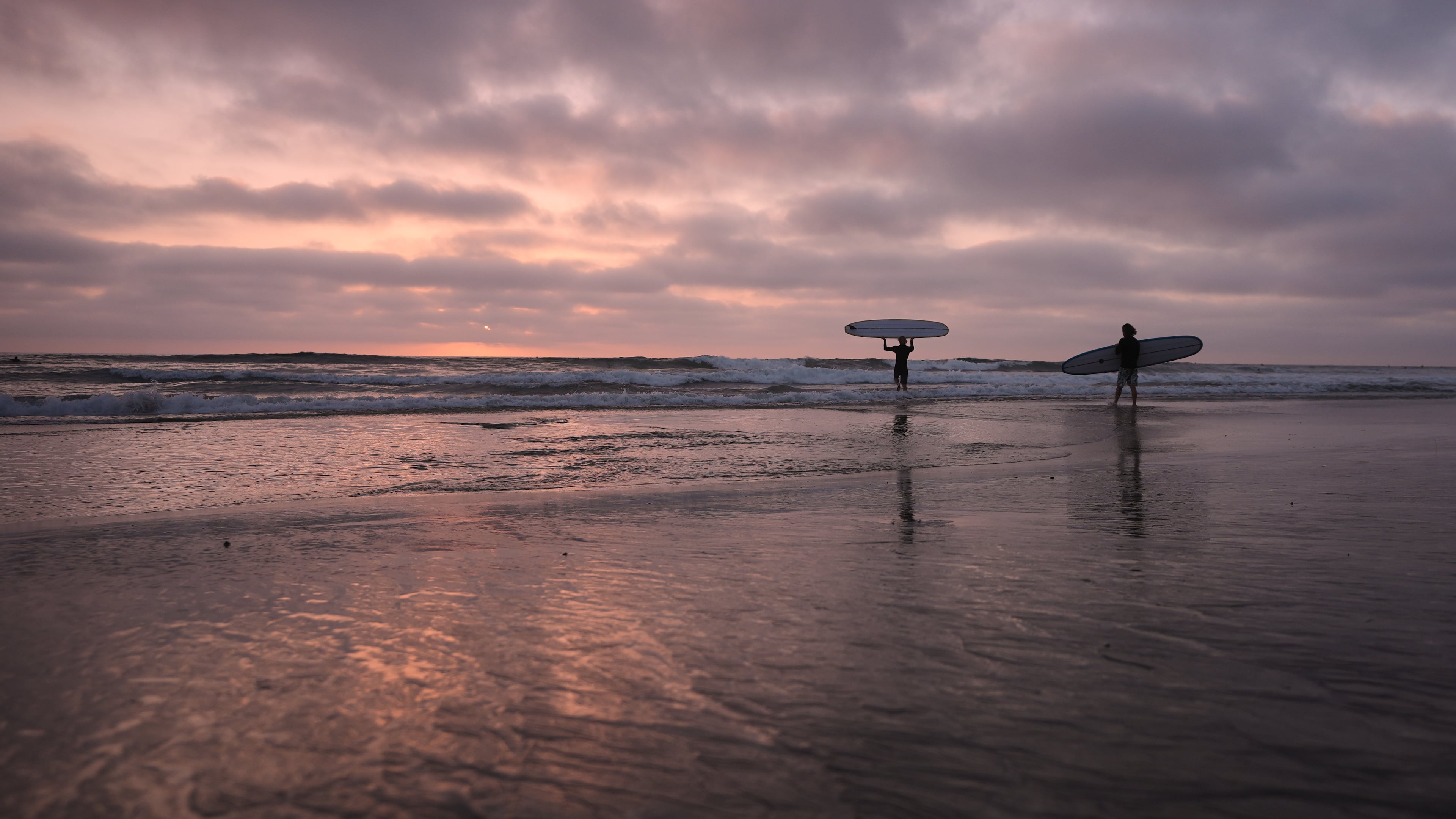 Surfers enter the Pacific Ocean as the sun sets Thursday, Oct. 1, 2026, in Encinitas, Calif. (AP Photo/Gregory Bull)
