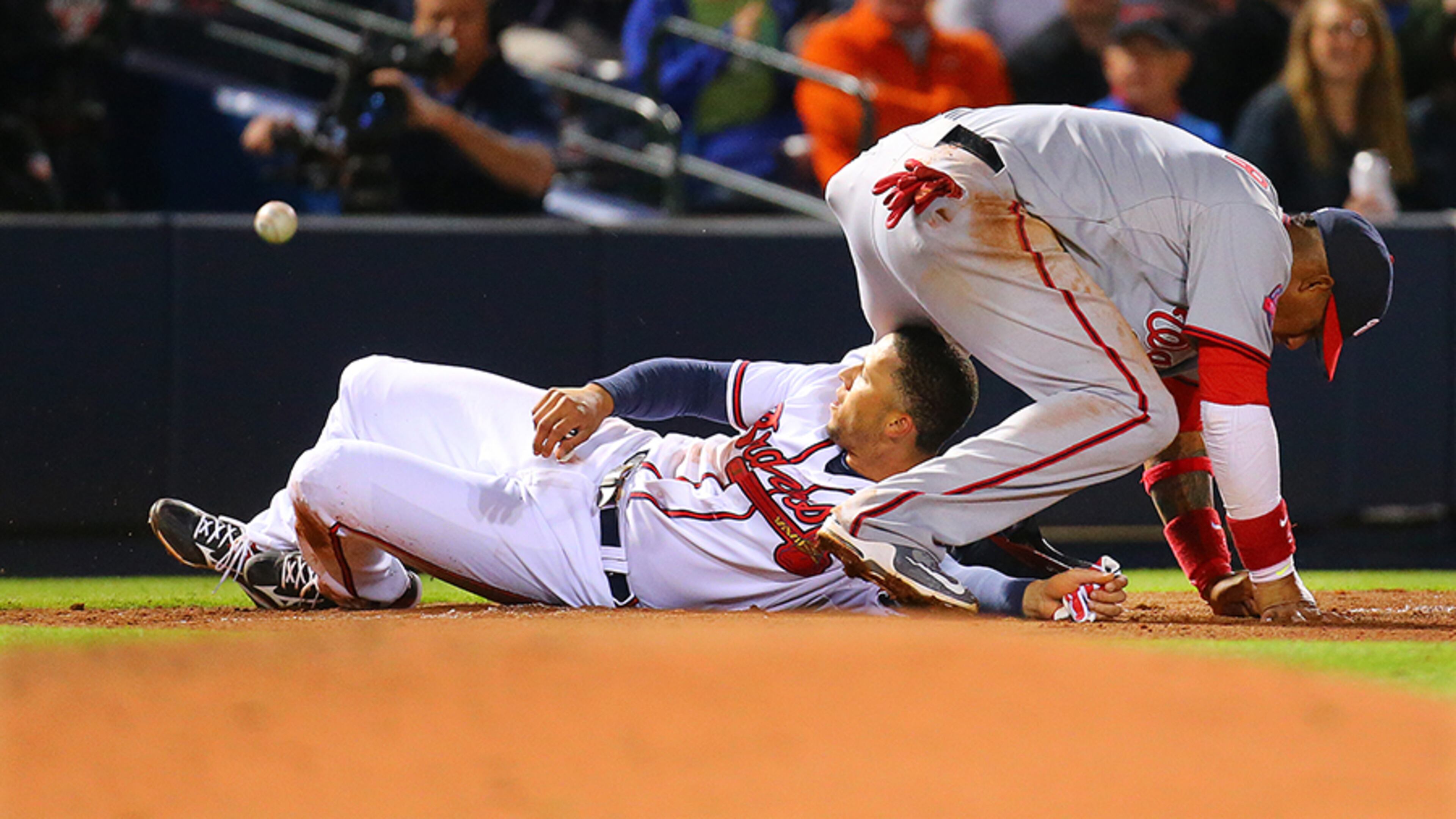 Braves shortsop Andrelton Simmons slides under the Nationals' Yunel Escobar safely at third base, advancing from first base on a wild pickoff attempt during the fifth inning. Escobar was injured on the play and left the game.
