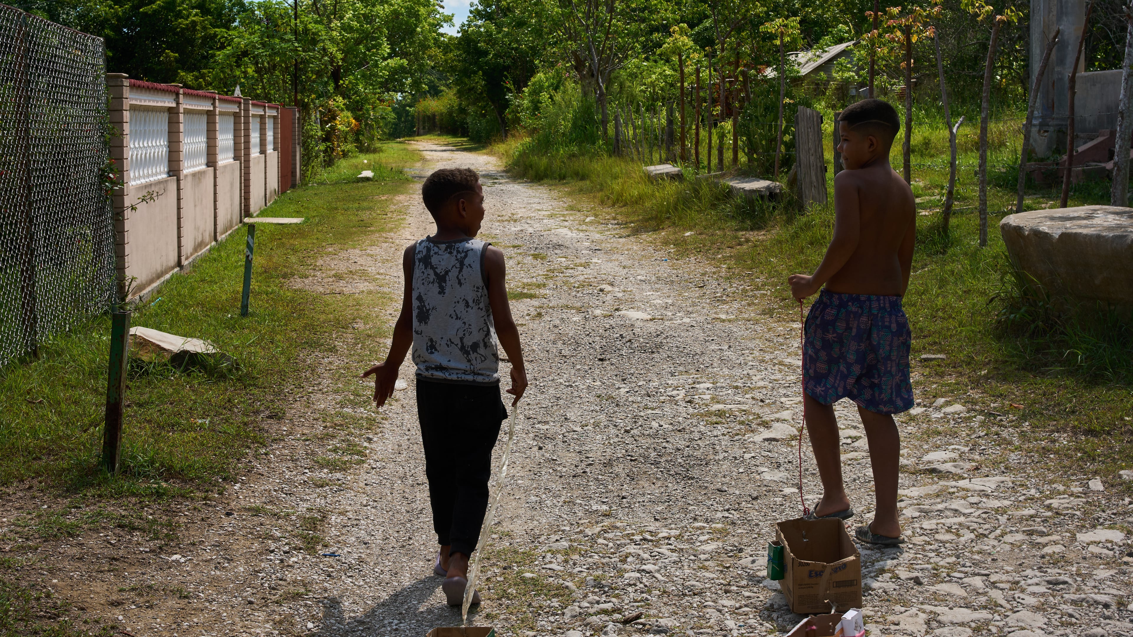 Children drag toys made from cardboard boxes as they walk in Minas, in Cuba's Havana province, Monday, Aug. 31, 2026. (AP Photo/Ramon Espinosa)
