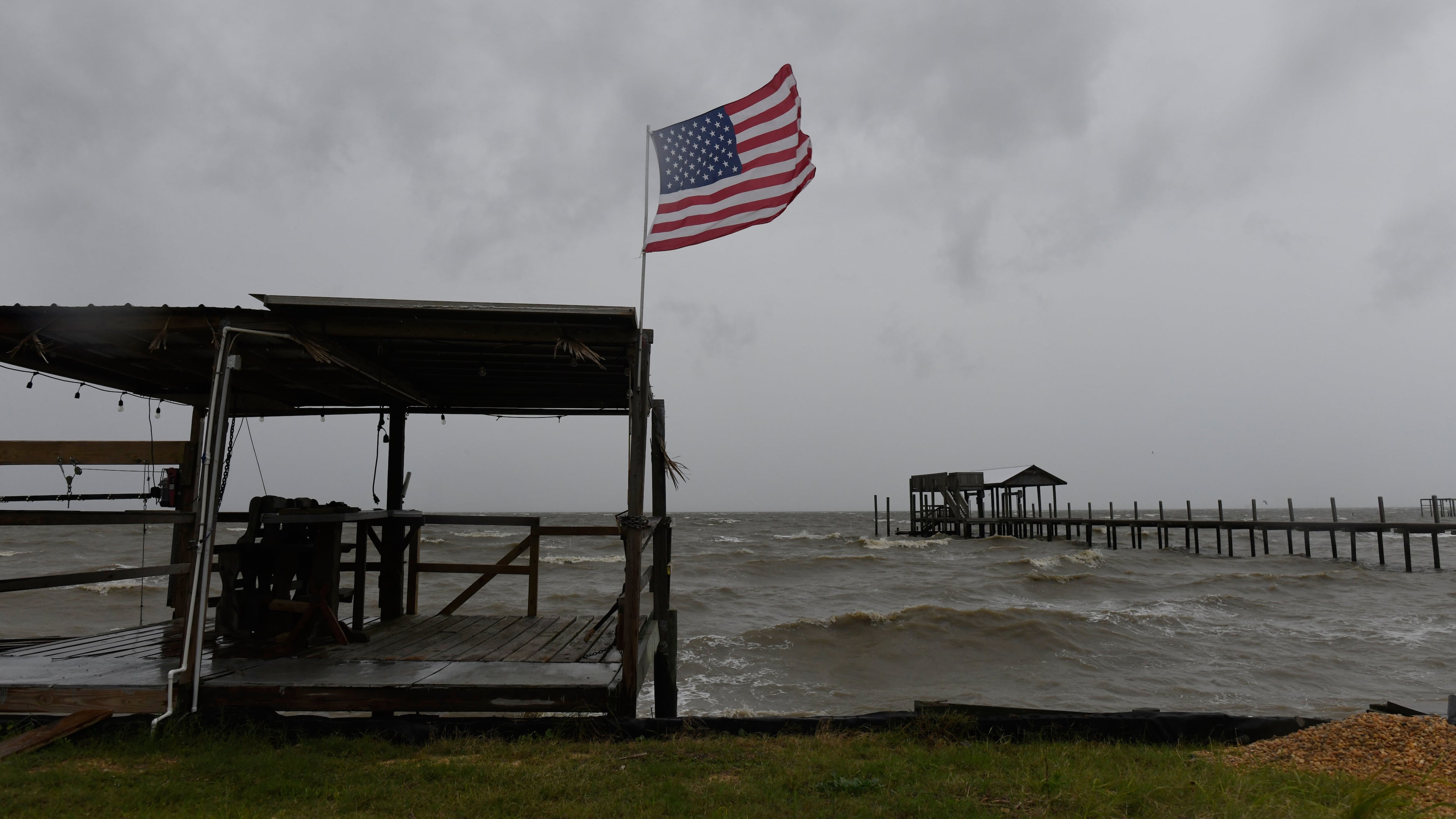 An American flag flaps in the wind generated by the effects of Isaias on an empty beach on Friday, Oct. 9, loom overhead on Friday, Oct. 9, 2026, in Mon Louis Island, Ala. (AP Photo/Octavio Jones)