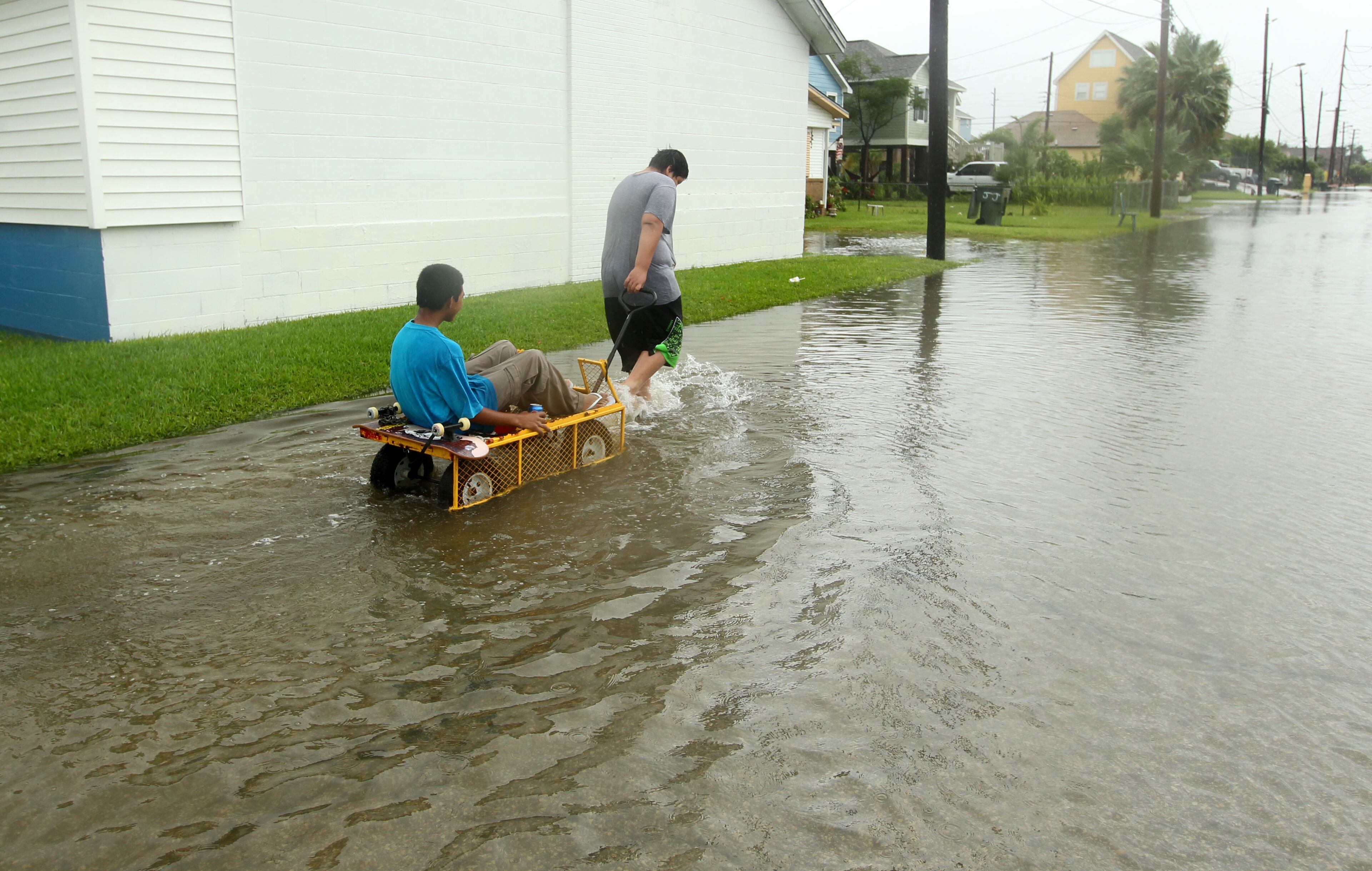 Manuel Martinez pulls Jesse McGehee through high water on Saladia Street in Galveston, Texas on Tuesday June 16, 2015. High tides cause by Tropical Storm Bill flooded several low-lying streets. (Jennifer Reynolds/The Galveston County Daily News via AP)