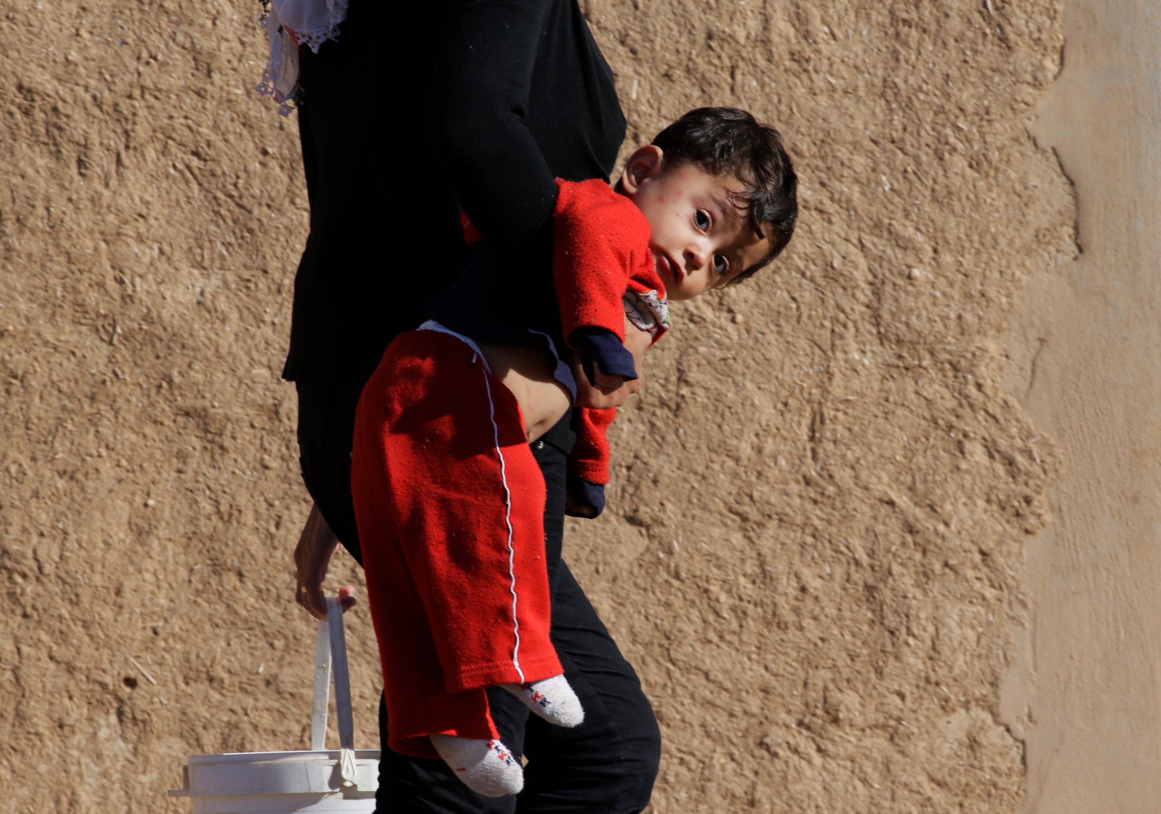 A Turkish Kurdish woman carries a child to a house in Mursitpinar, in the outskirts of Suruc, on the Turkey-Syria border, as the fighting between militants of the Islamic State group and Kurdish forces intensified in nearby Kobani, Syria, Tuesday, Oct. 7, 2014. Kobani, also known as Ayn Arab and its surrounding areas have been under attack since mid-September, with militants capturing dozens of nearby Kurdish villages.(AP Photo/Lefteris Pitarakis)