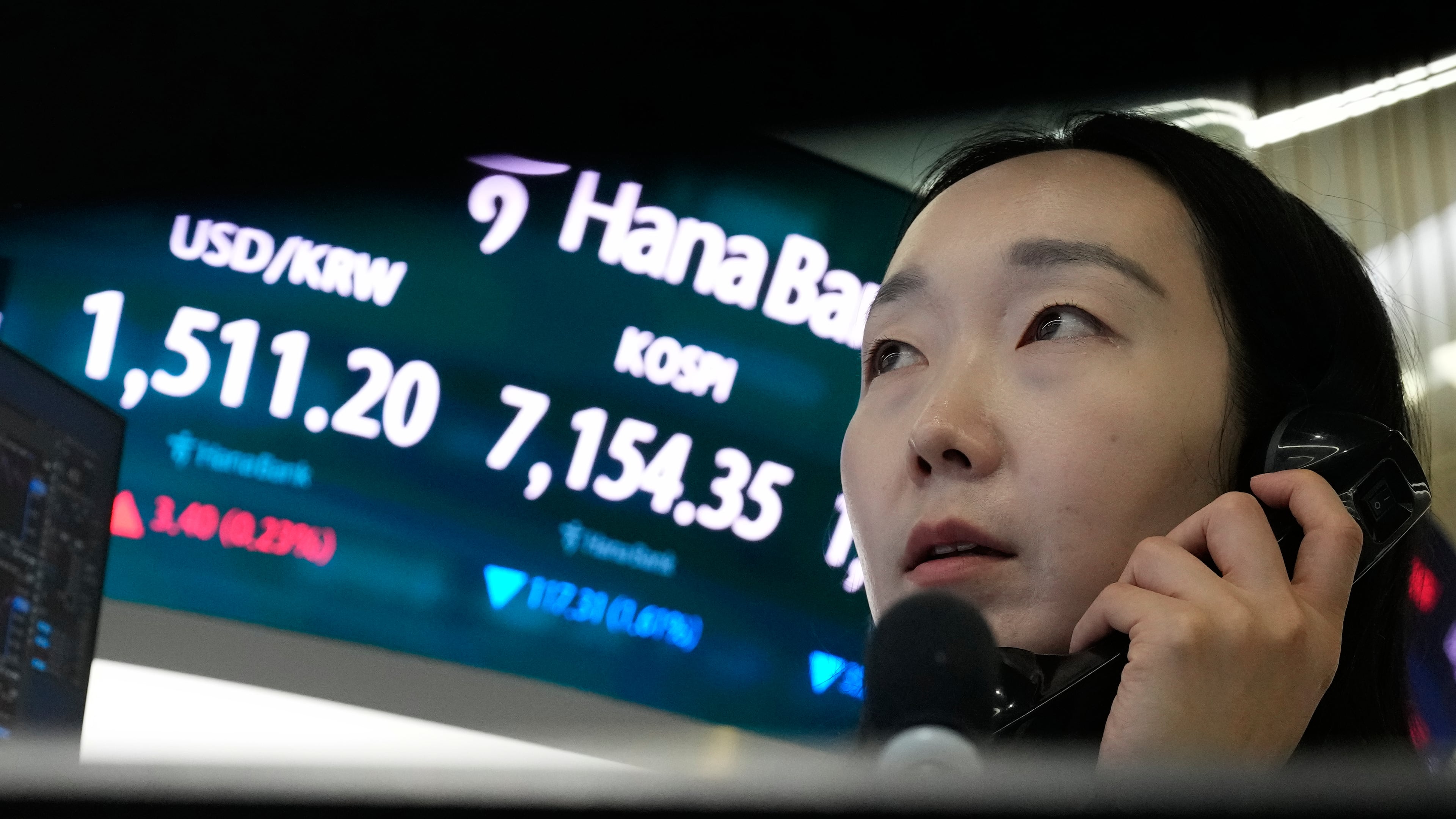 A currency trader talks on the phone near a screen showing the Korea Composite Stock Price Index (KOSPI) and the foreign exchange rate between U.S. dollar and South Korean won, left, at the foreign exchange dealing room of the Hana Bank headquarters in Seoul, South Korea, Wednesday, May 20, 2026. (AP Photo/Ahn Young-joon)