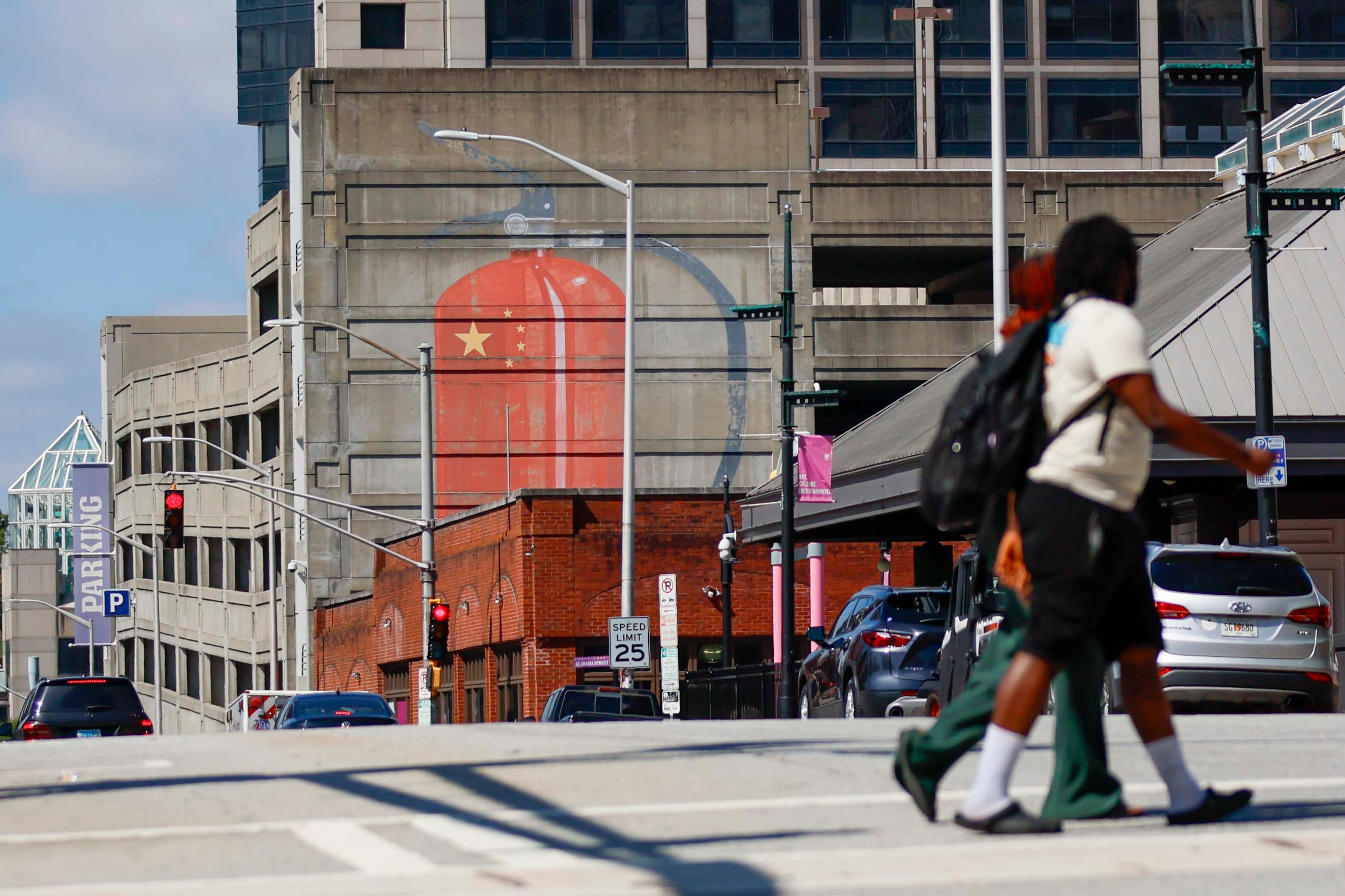 People cross Pryor Street at the intersection with Wall Street in downtown Atlanta, where a large mural of a fire extinguisher with the Chinese flag is displayed. The mural is by Escif, a Spanish street artist. (Miguel Martinez/AJC)