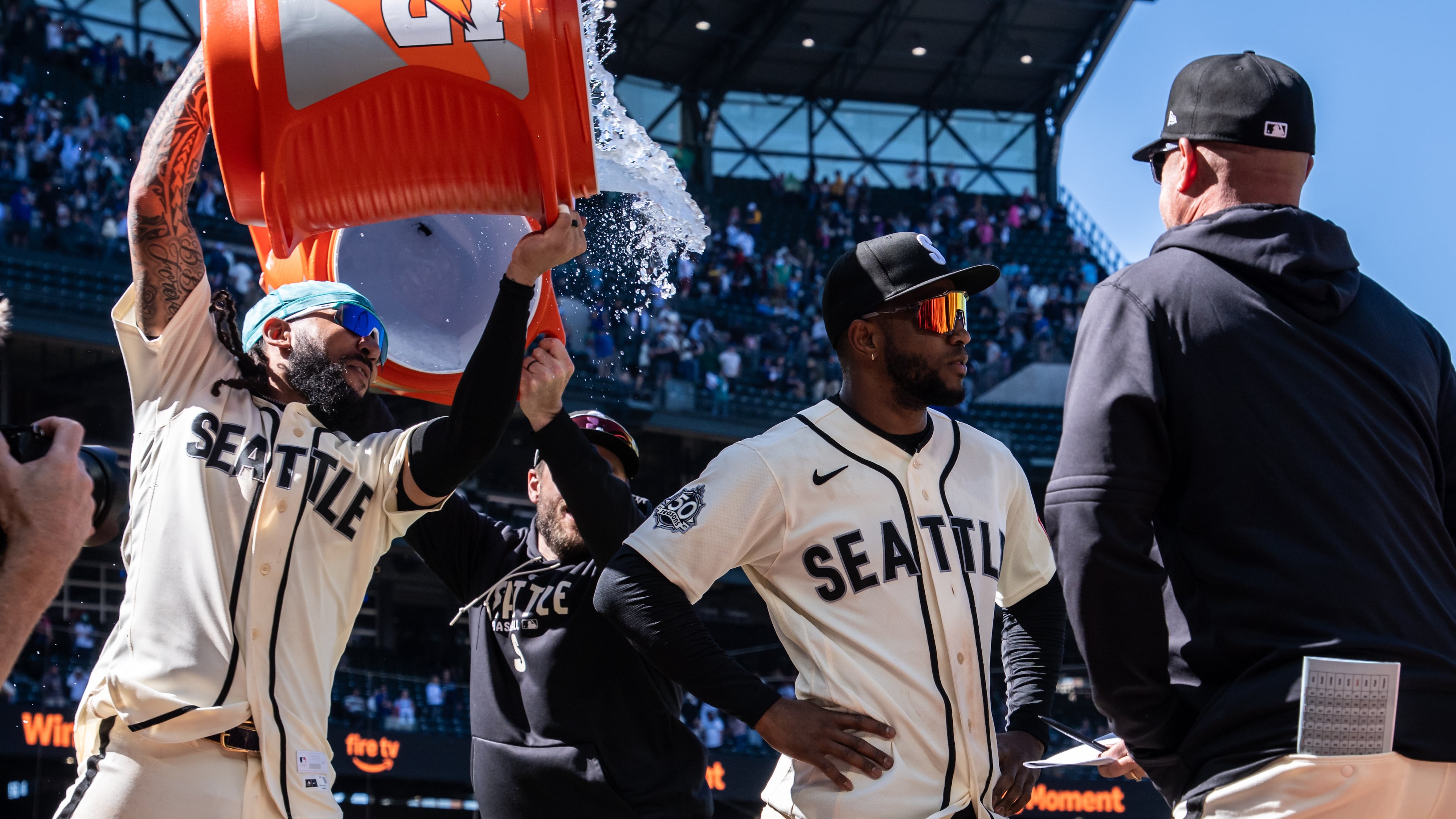 Seattle Mariners' J.P. Crawford, left, douses Victor Robles, second from right, after a baseball game against the Arizona Diamondbacks, Sunday, May 31, 2026, in Seattle. (AP Photo/Stephen Brashear)