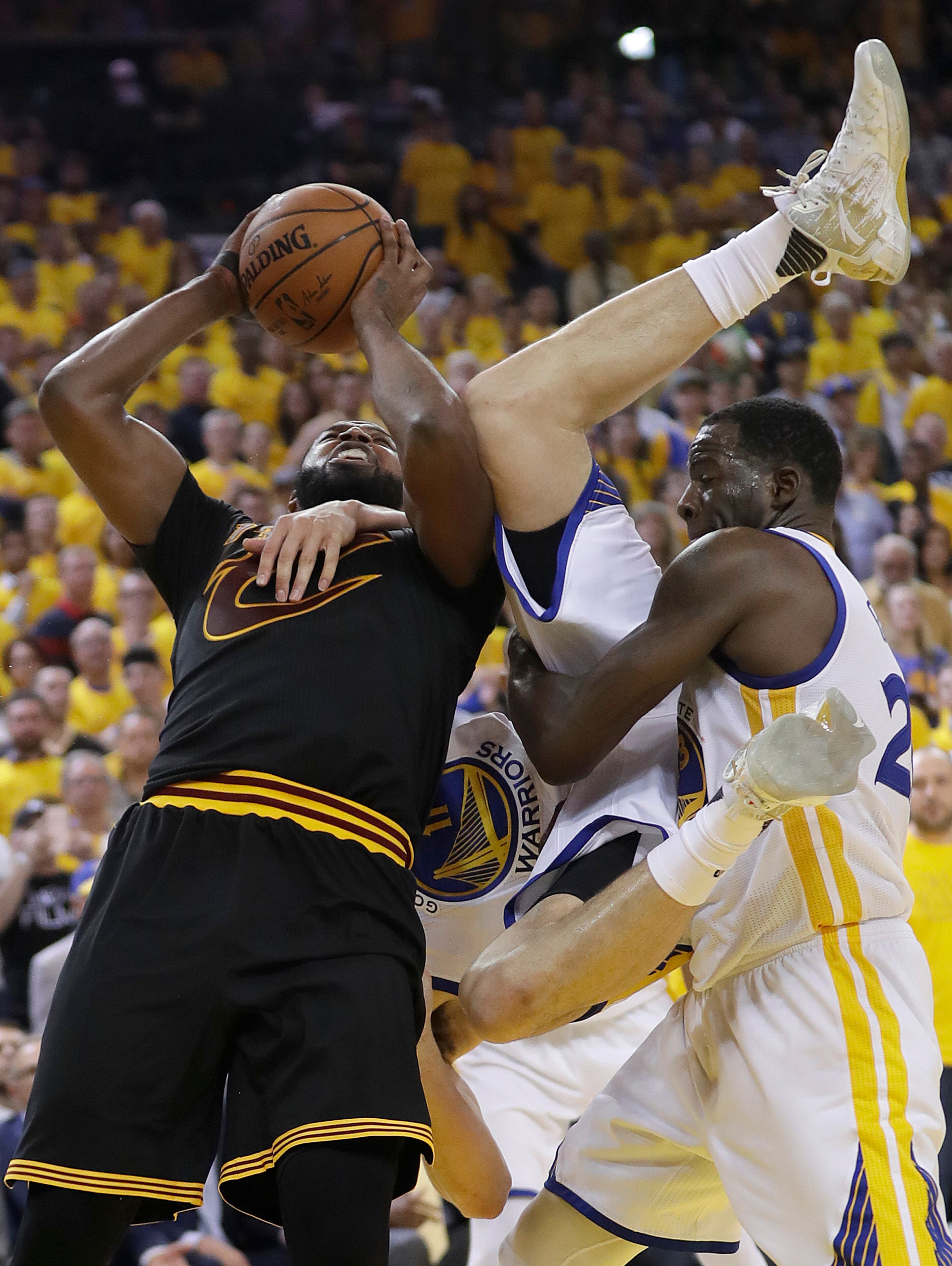 Cleveland Cavaliers center Tristan Thompson, left, shoots as Golden State Warriors guard Klay Thompson, center, is held by forward Draymond Green during the second half of Game 5 of basketball's NBA Finals in Oakland, Calif., Monday, June 12, 2017. (AP Photo/Marcio Jose Sanchez)
