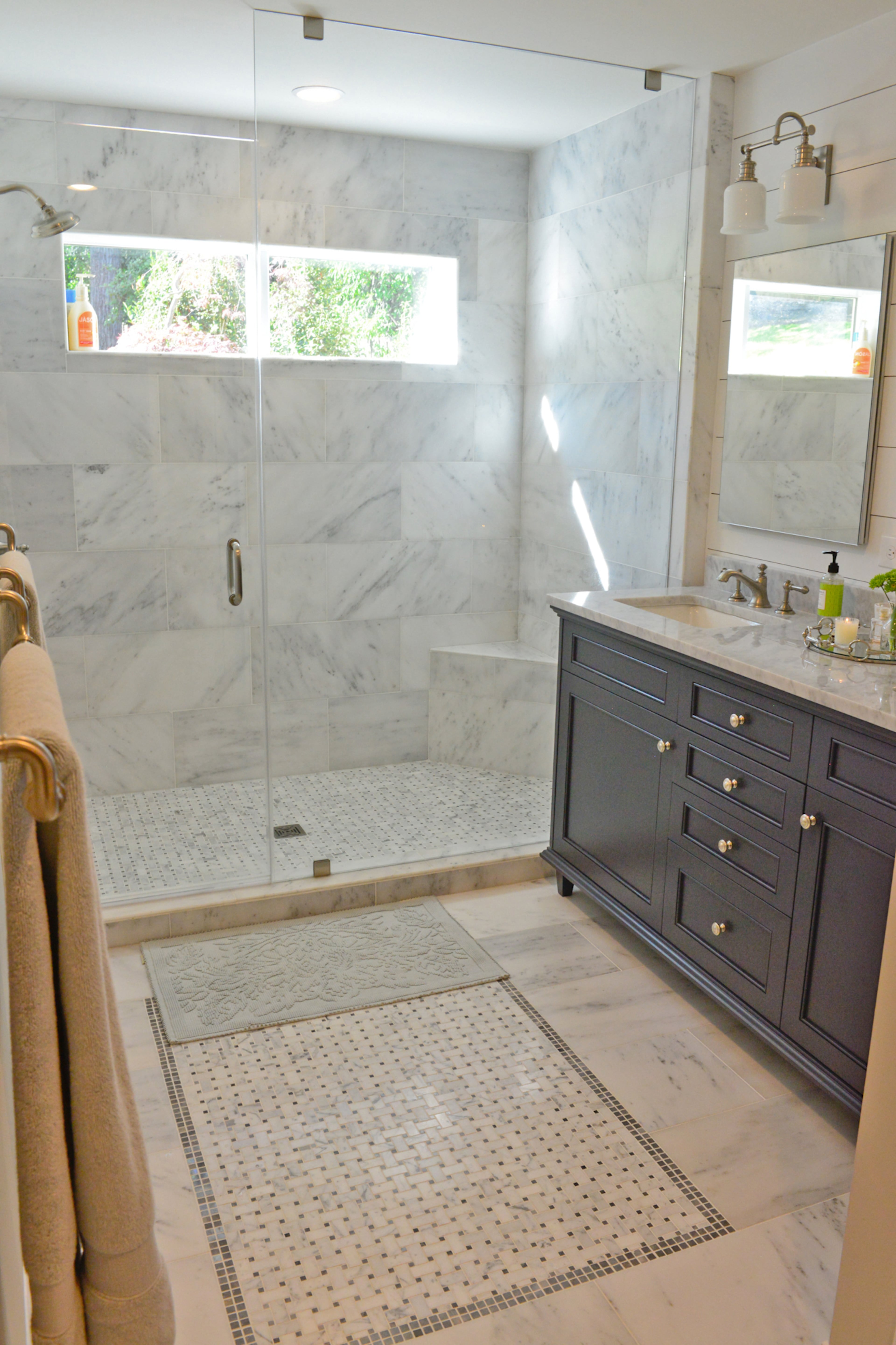 The new master bathroom incorporates black and white tiles from Moda Floors & Interiors into a marble “floor rug” with modern updates including a frameless shower.