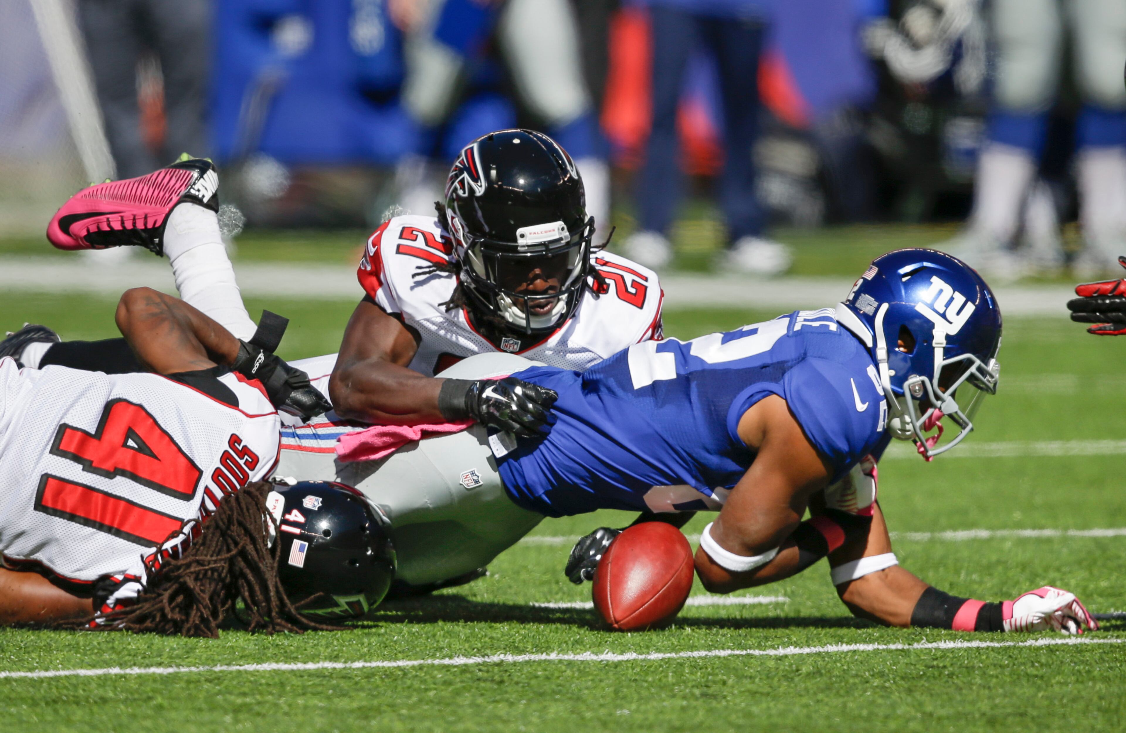 New York Giants wide receiver Rueben Randle, right, fumbles the ball while being tackled by Atlanta Falcons free safety Dezmen Southward (41) and cornerback Desmond Trufant (21) during the first half of an NFL football game, Sunday, Oct. 5, 2014, in East Rutherford, N.J. The Giants recovered the ball on the play. (AP Photo/Seth Wenig)