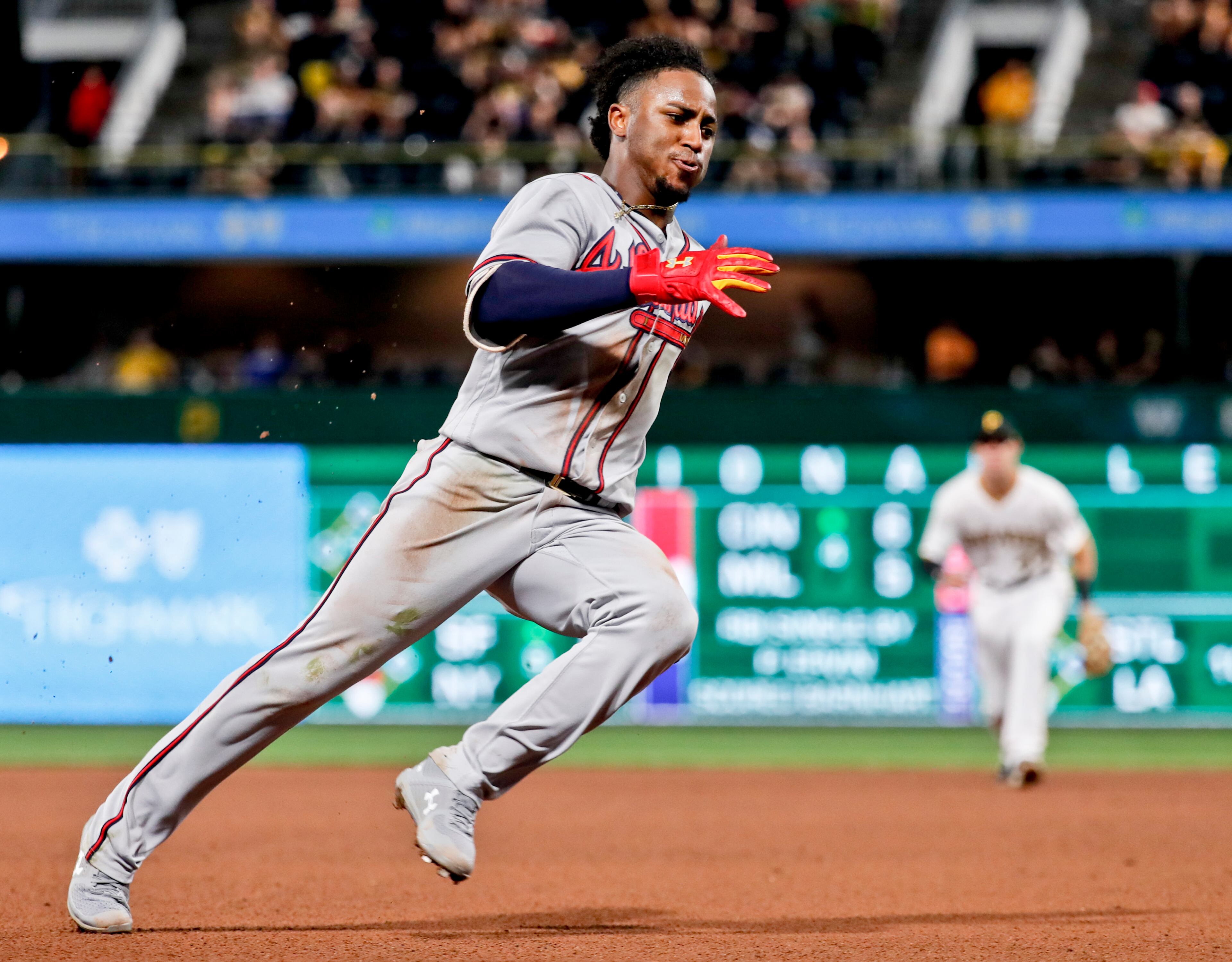 Atlanta Braves' Ozzie Albies, left rounds third and heads home to score from first past Pittsburgh Pirates second baseman Kevin Newman, right, on a double by Kurt Suzuki in the seventh inning of a baseball game, Tuesday, Aug. 21, 2018, in Pittsburgh. (AP Photo/Keith Srakocic)