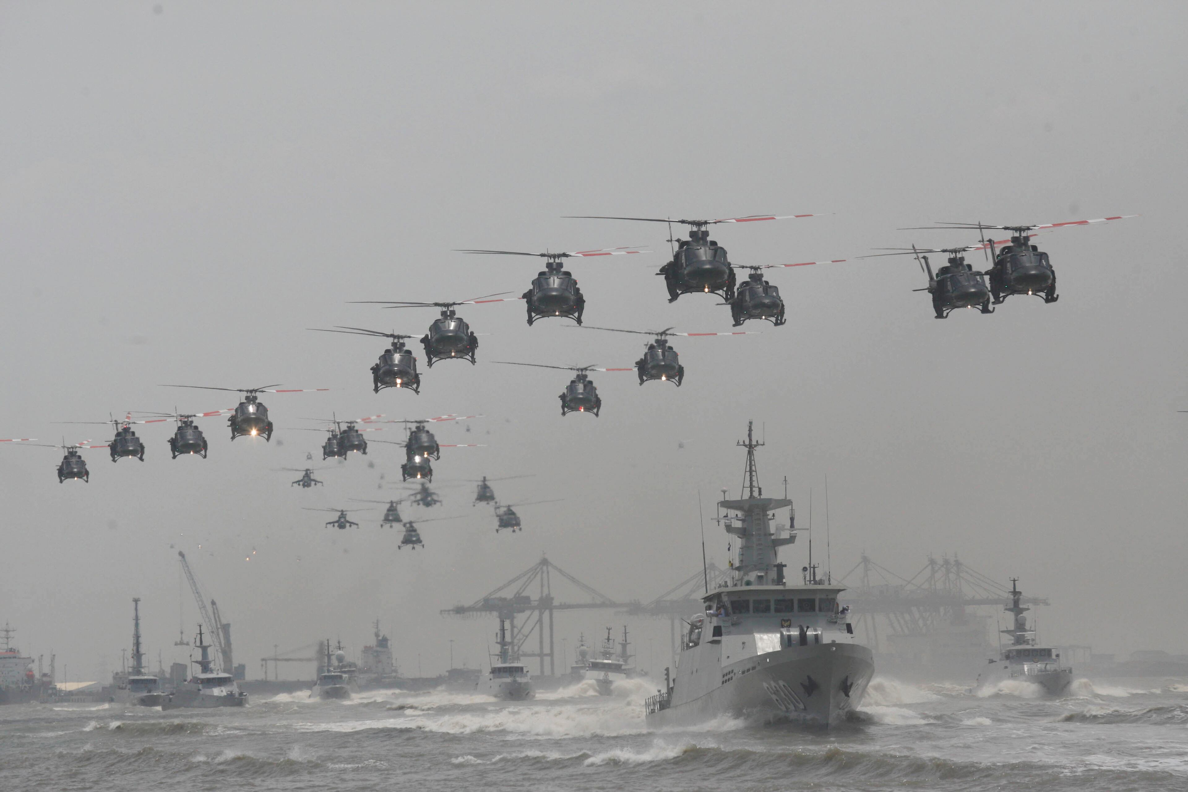 Indonesian Air Force helicopters fly in formation over the fleet of military ships in a show of force during a ceremony commemorating the 69th anniversary of Indonesian Armed Forces in Surabaya, East Java, Indonesia, Tuesday, Oct. 7, 2014. (AP Photo/Trisnadi)