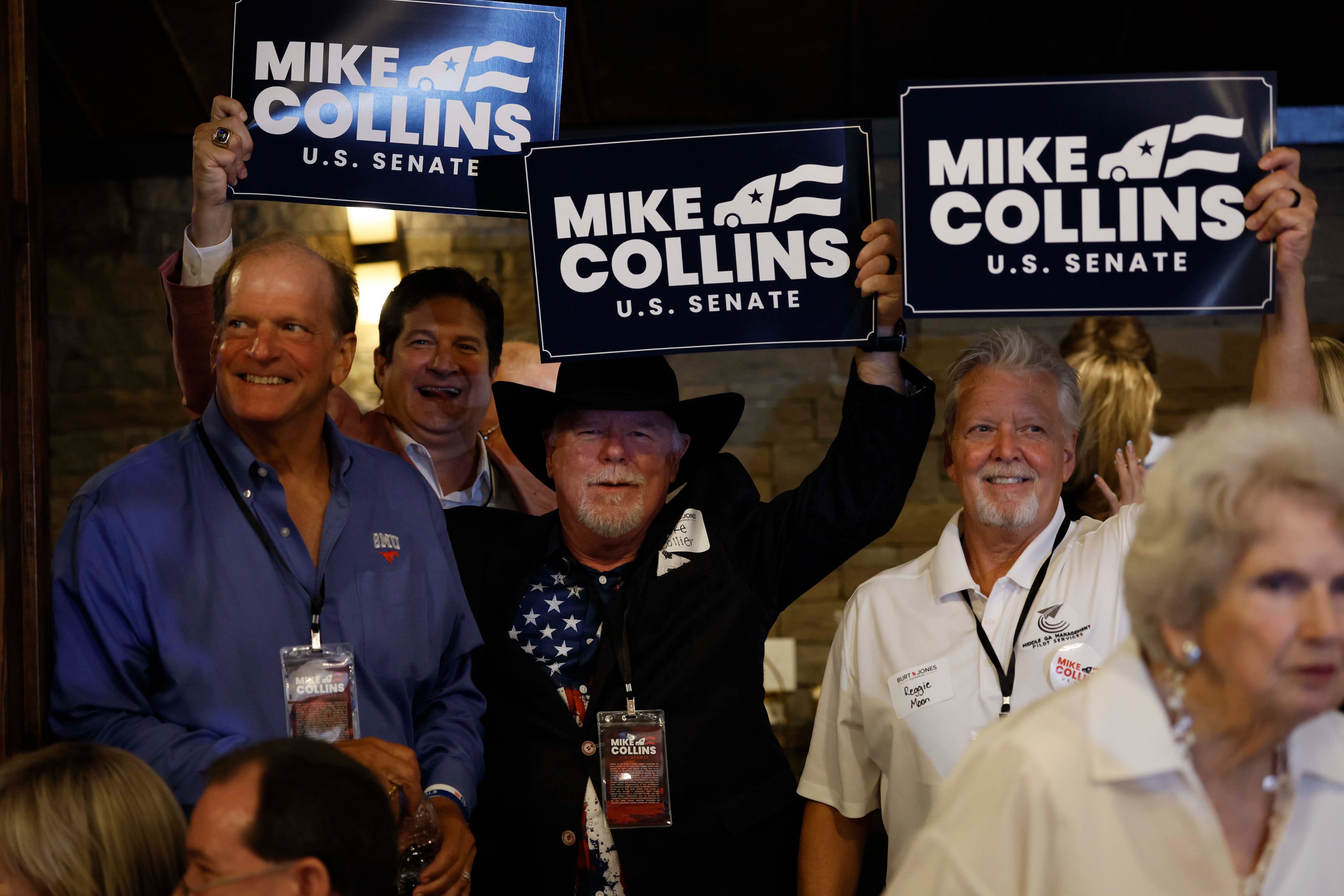 Supporters of U.S. Rep. Mike Collins hold banners during an runoff election night watch last month at Seven Oaks Manor in Jackson. (Miguel Martinez/AJC)